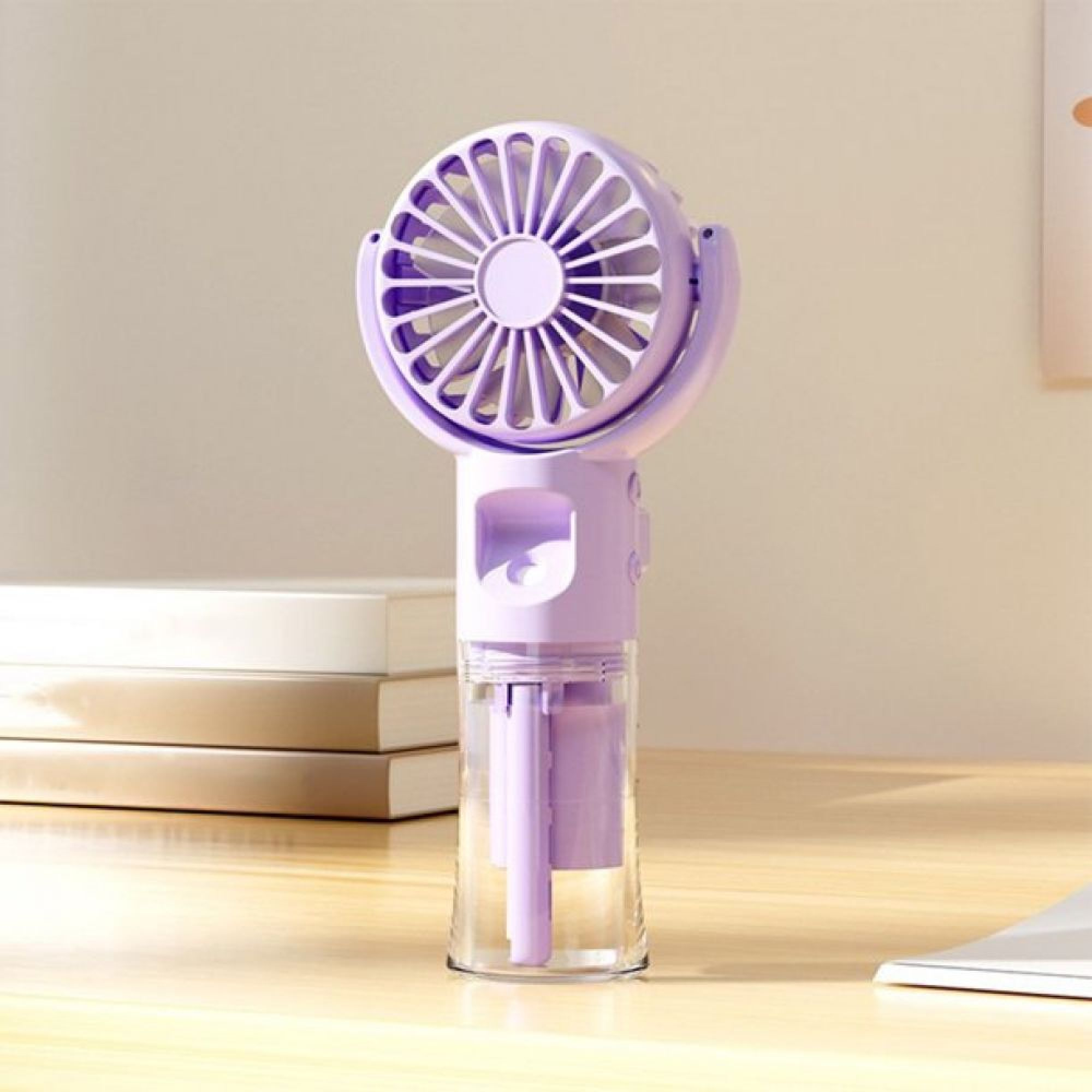 Ein violetter Handventilator mit transparentem Behälter steht auf einem Schreibtisch neben Büchern.