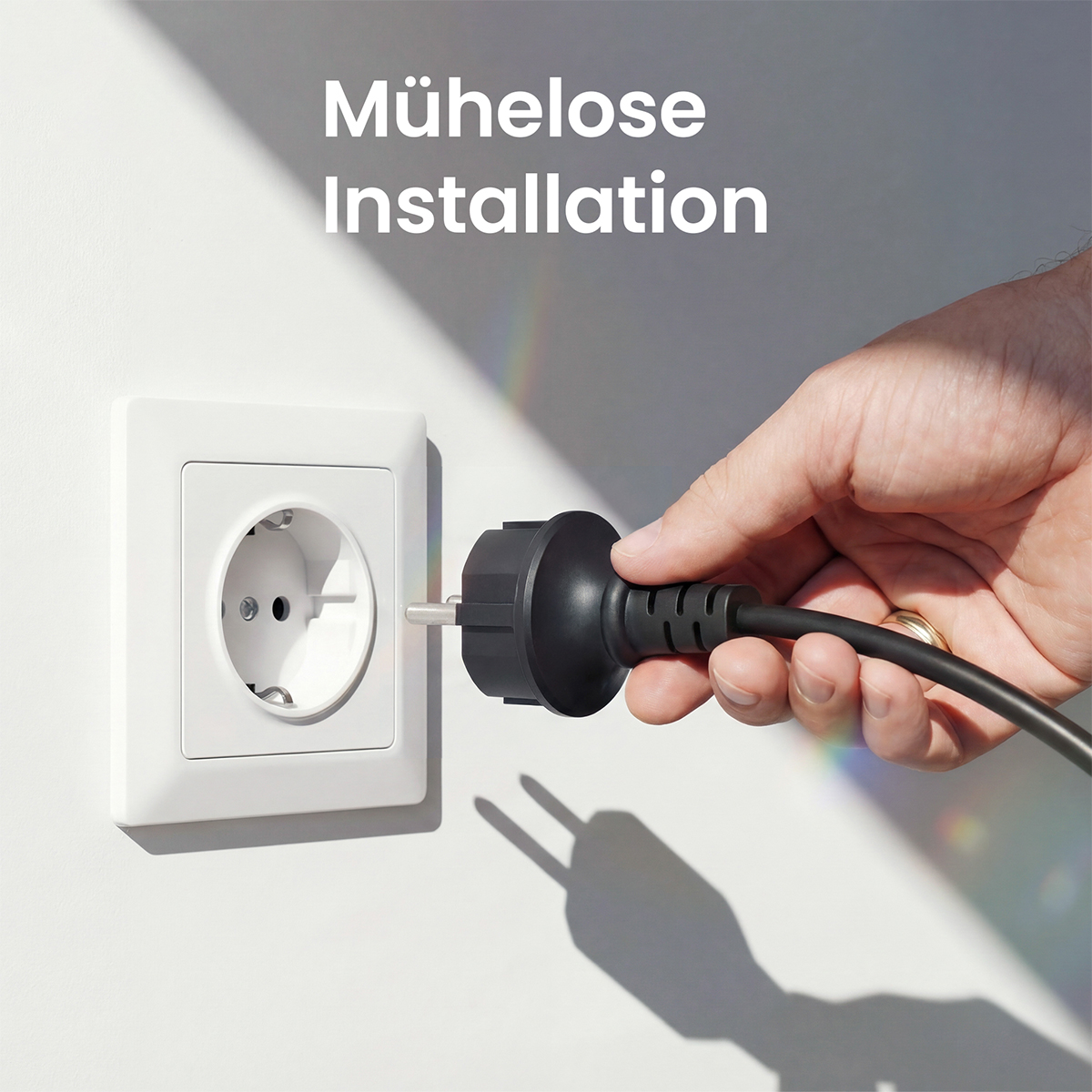 Eine Hand steckt einen schwarzen Stecker in eine weiße Steckdose.