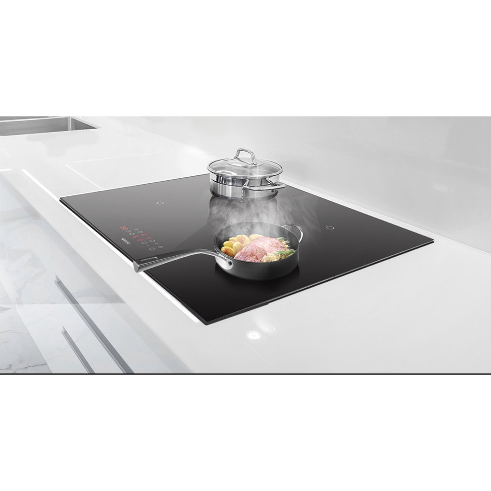 Een inductiekookplaat met een pan vlees en aardappelen en een pot.