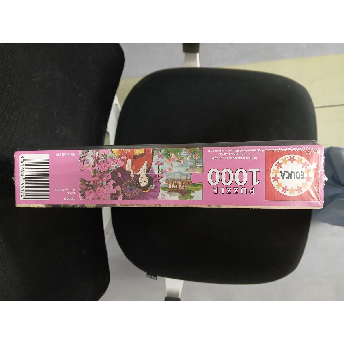 Una caja de rompecabezas con arte japonés: una mujer en kimono, flores de cerezo y un puente.