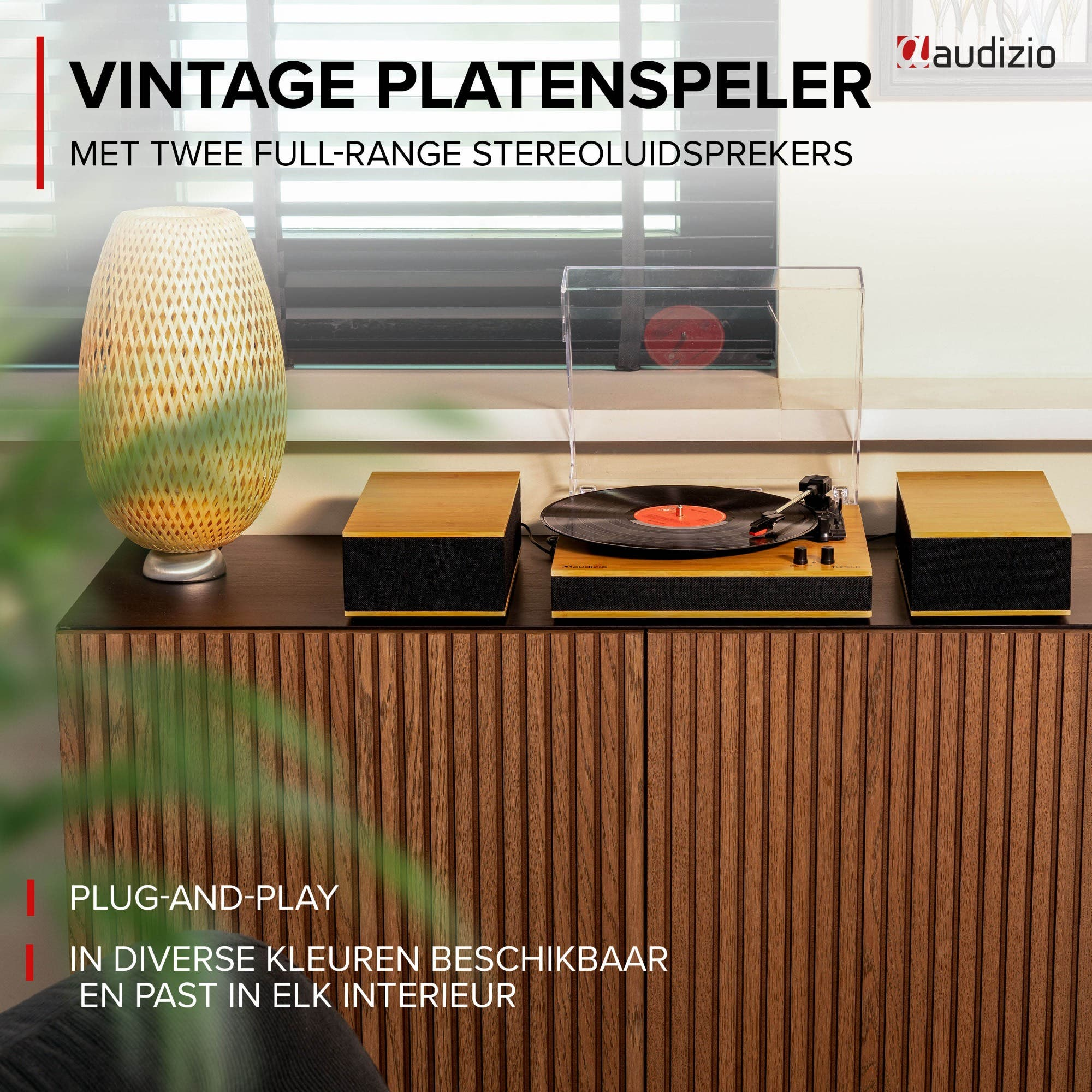A record player with two speakers on a wooden cabinet next to a vase.