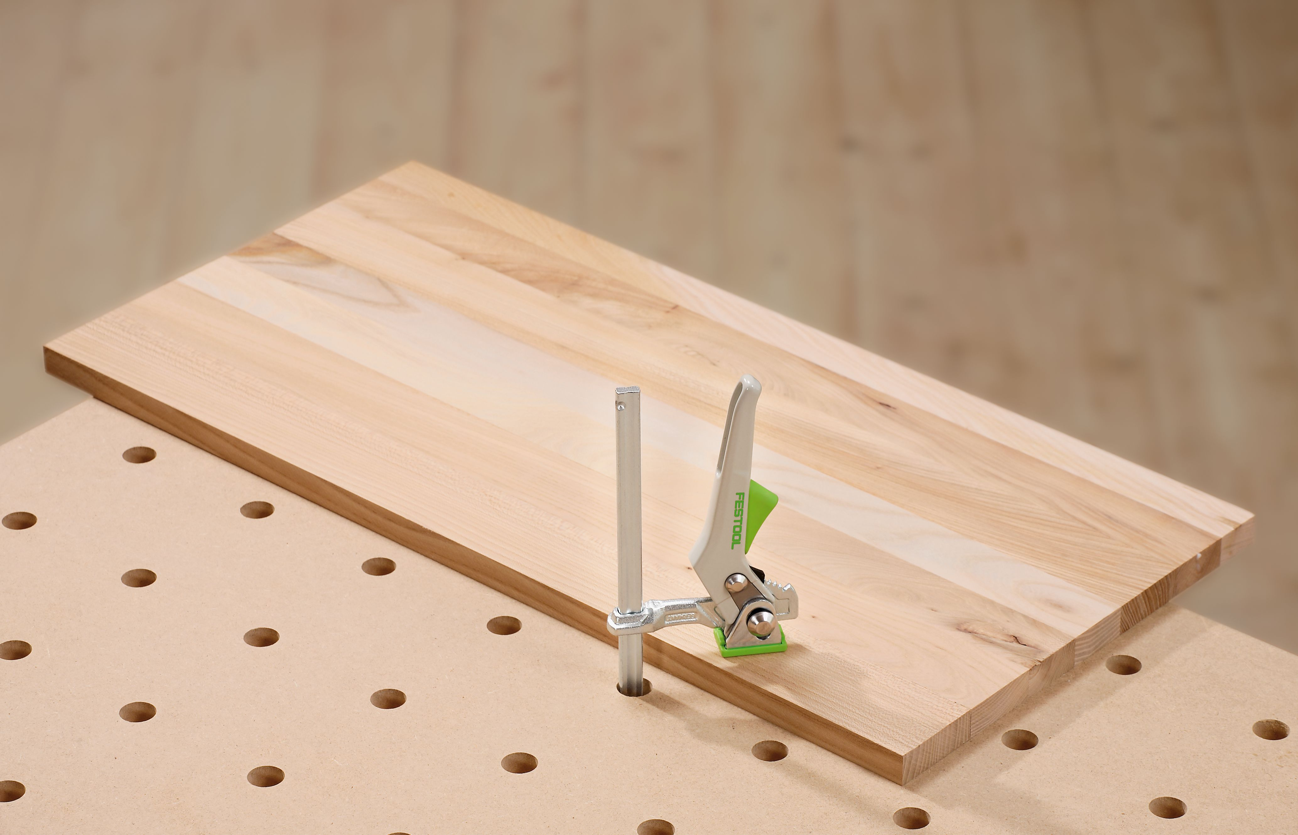 Ein Holzbalken wird auf einer Lochplatte mit einer Festool-Klemme fixiert.