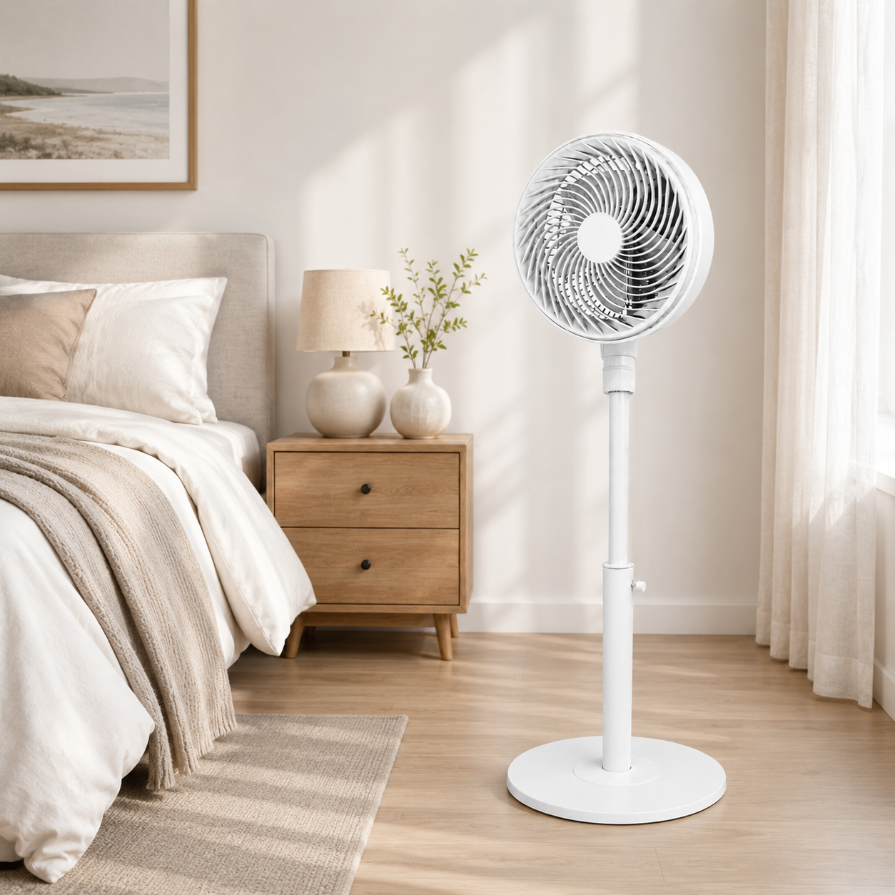 Un ventilador de pie blanco está junto a una cama con mesita de noche y lámpara.