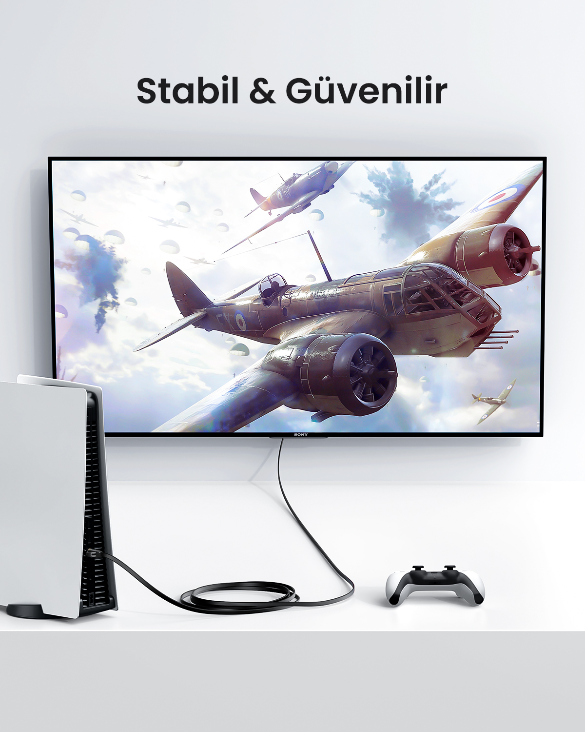 Bir TV ekranı önünde kablosu ve kontrolcüsü olan beyaz oyun konsolu.