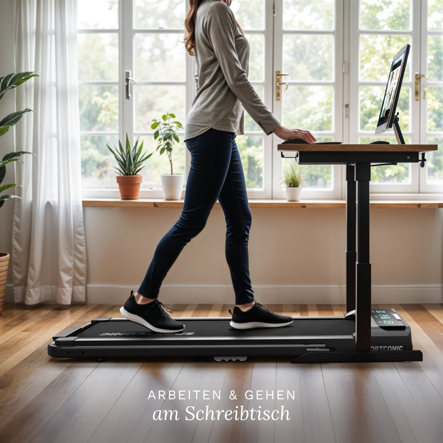 Een vrouw loopt op een loopband onder een bureau met een monitor.