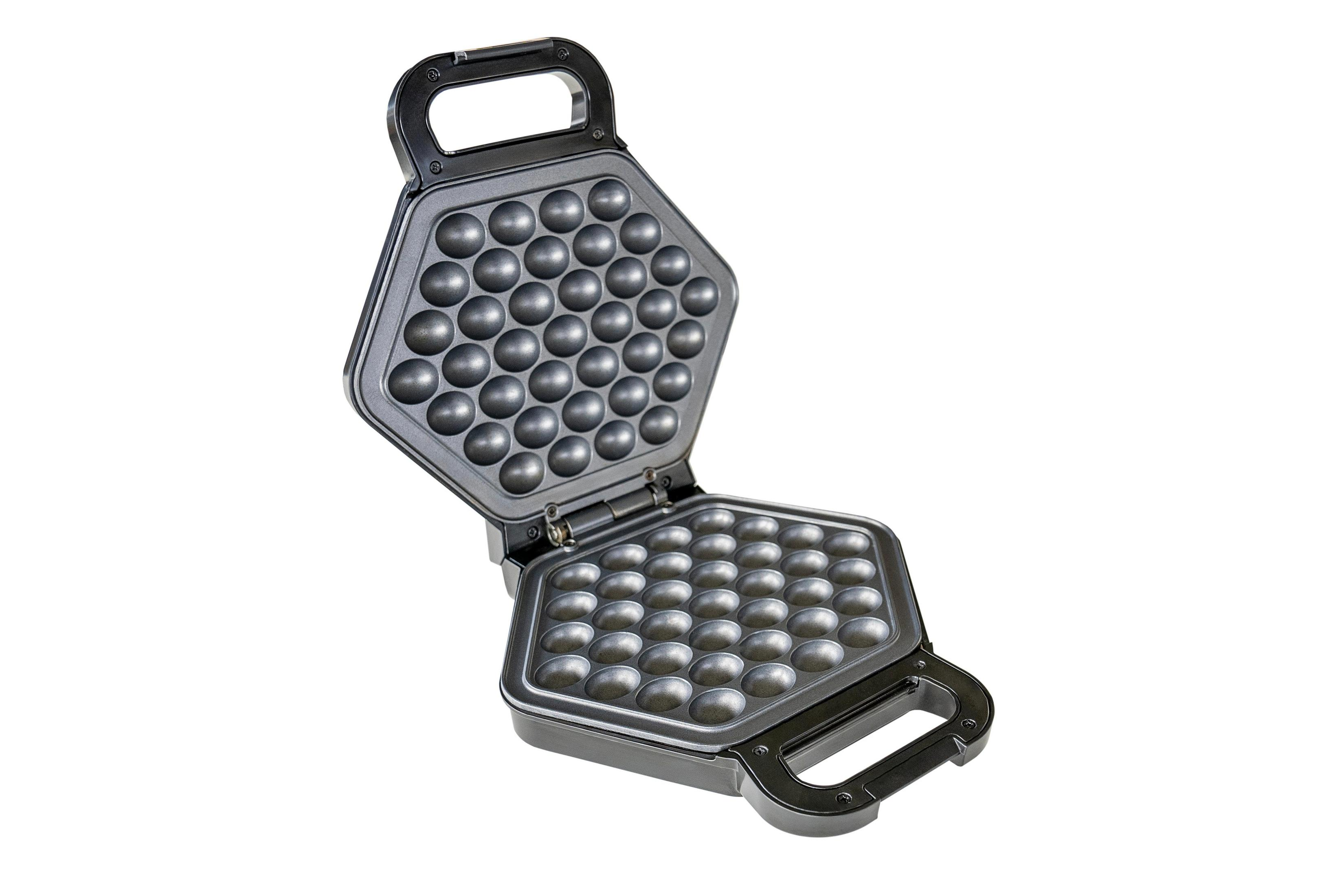 Una piastra per waffle a bolle aperta e grigia di forma esagonale con molte rientranze rotonde.