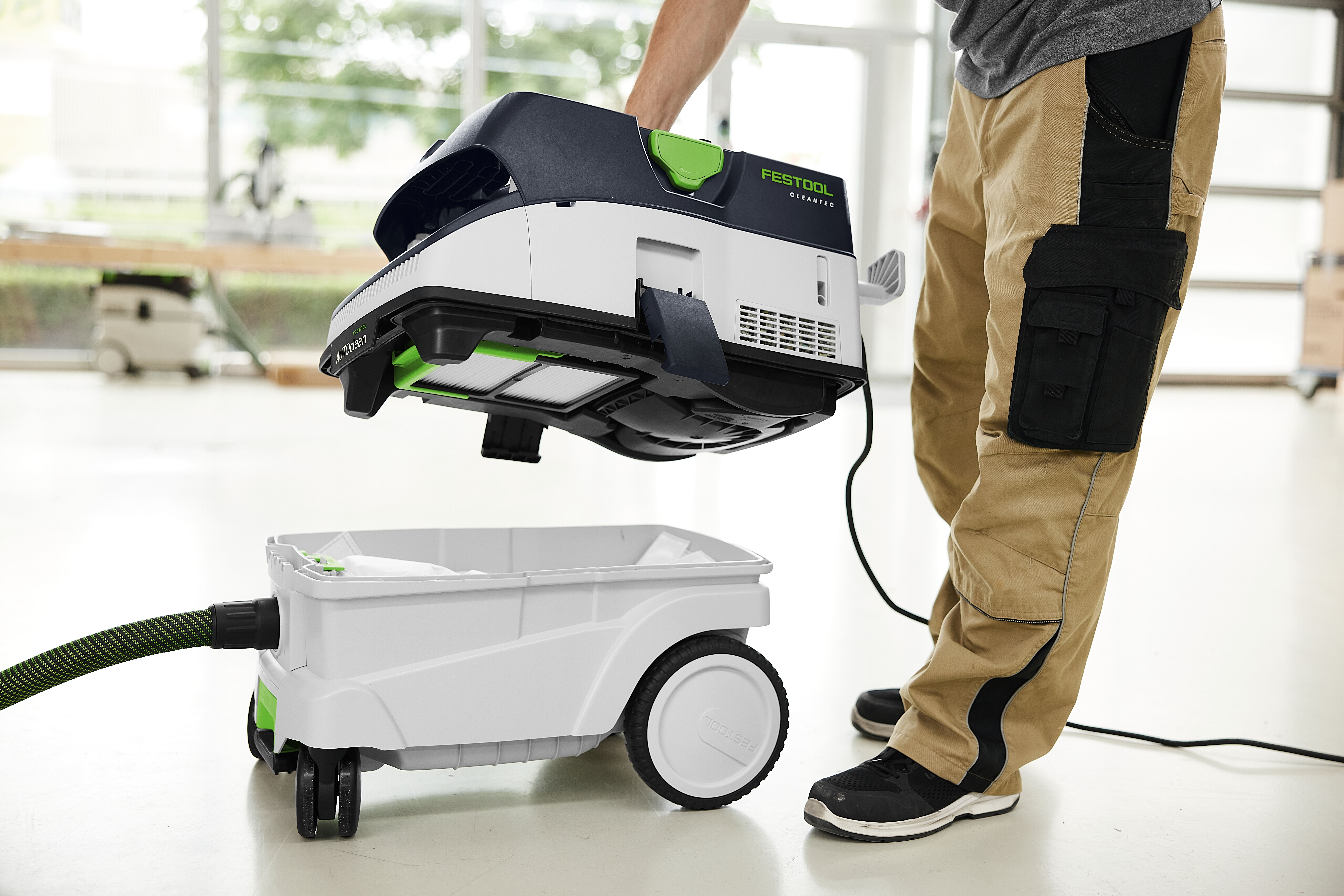 Ein Mann montiert einen schwarzen und weißen Festool Staubsauger auf eine weiße mobile Einheit.