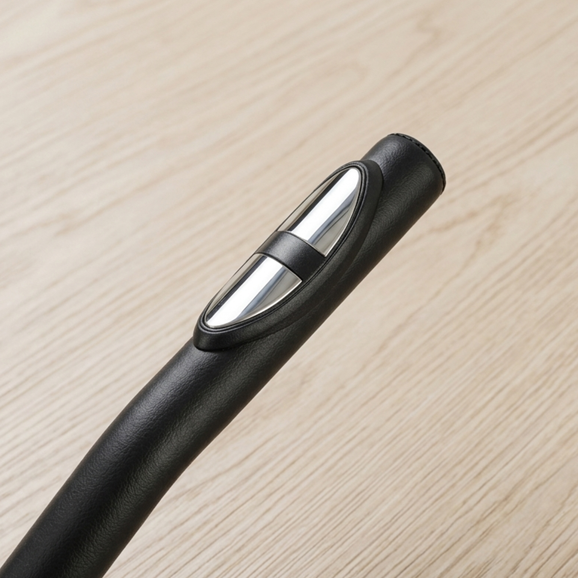 Manico nero con accento argentato su sfondo di legno chiaro.