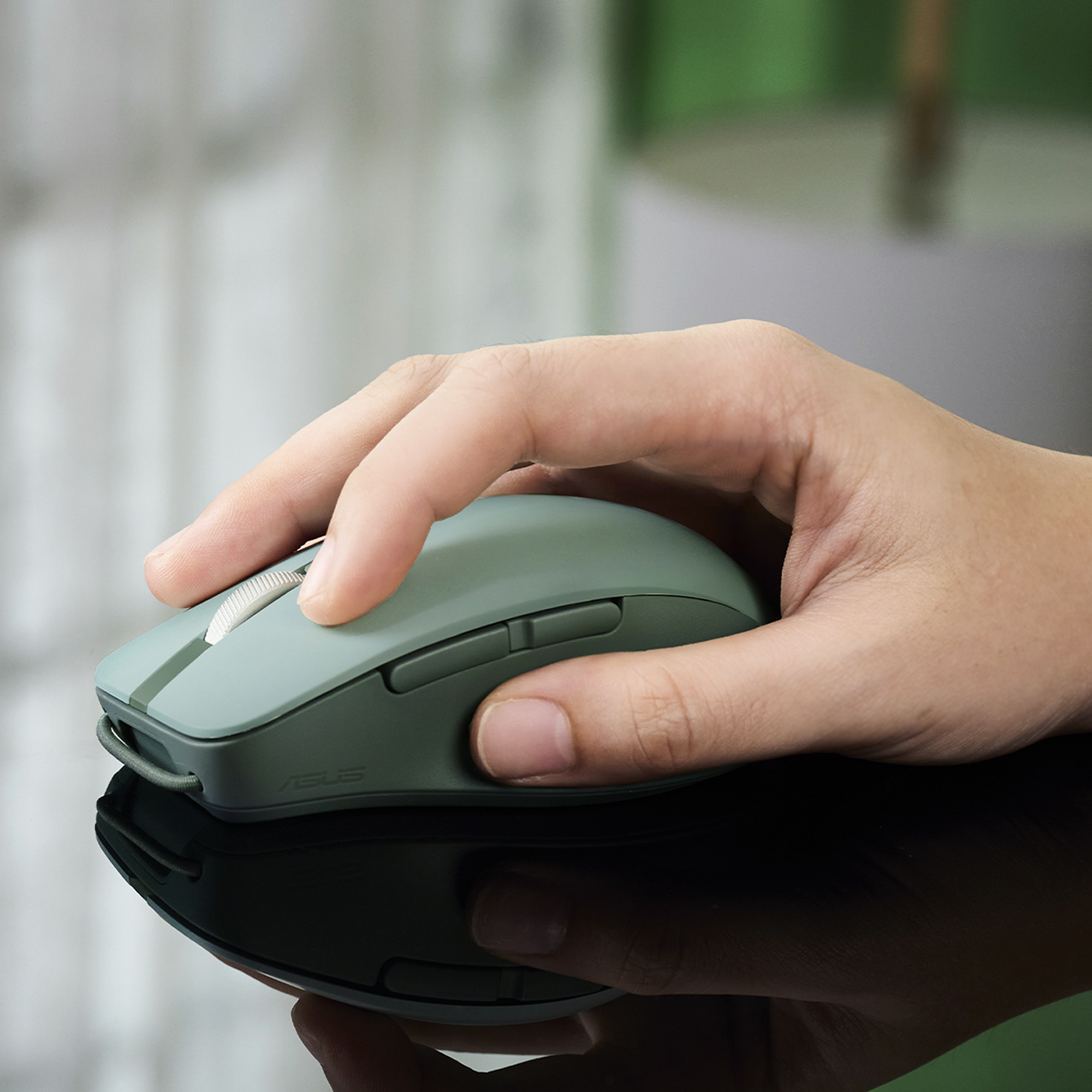 Una mano aziona un mouse verde su una superficie lucida.