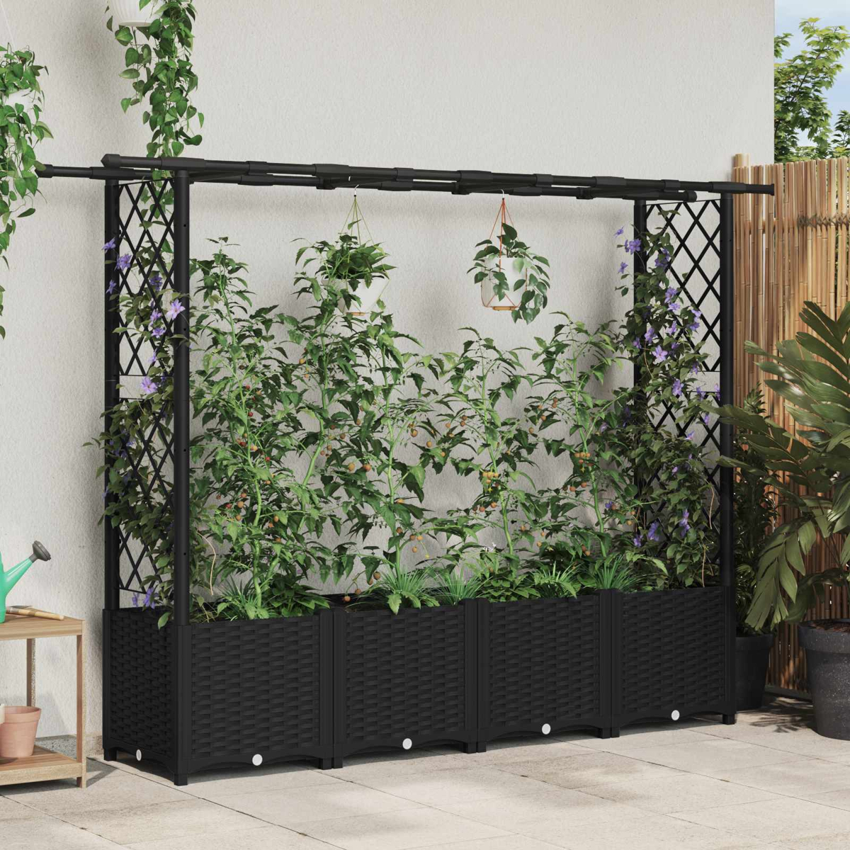 Ein schwarzes Hochbeet mit Kletterpflanzen und Blumen vor einer weißen Wand.