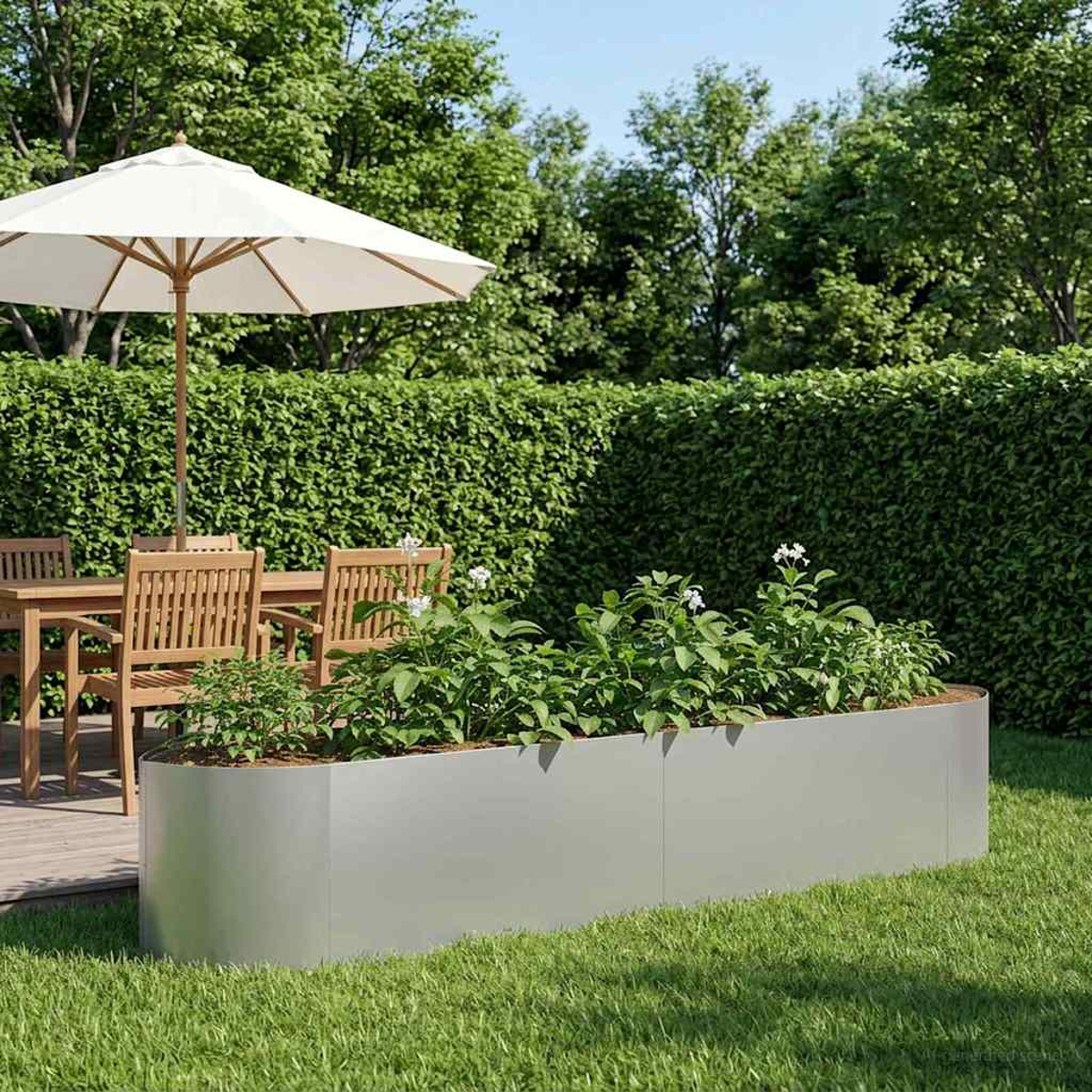 Ein rechteckiger Hochbeet aus Metall steht auf einem gepflegten Rasen, daneben ein Gartentisch mit Stühlen.
