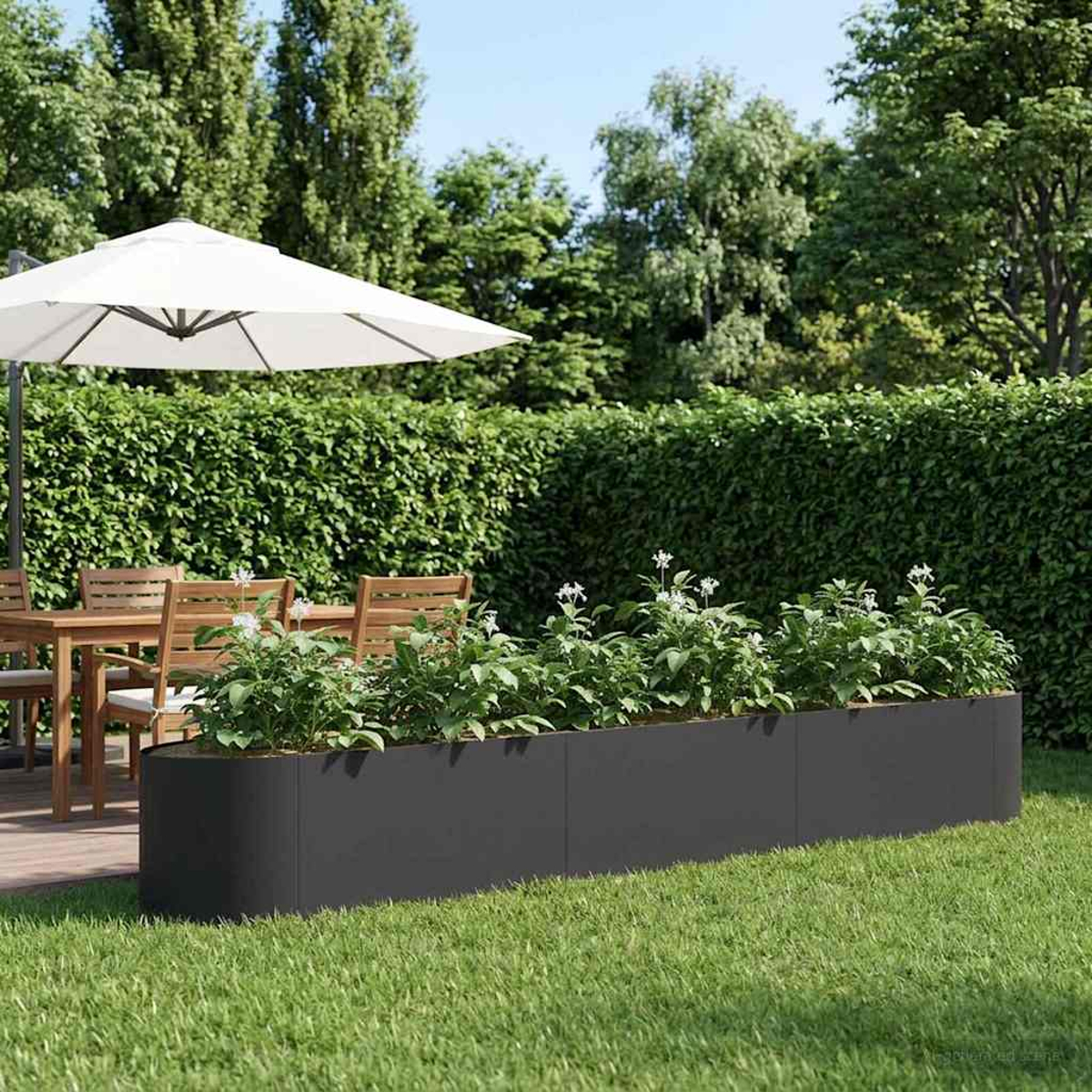 Ein Garten mit Tisch, Stühlen, Sonnenschirm, Hecke und einem langen Blumenkasten.
