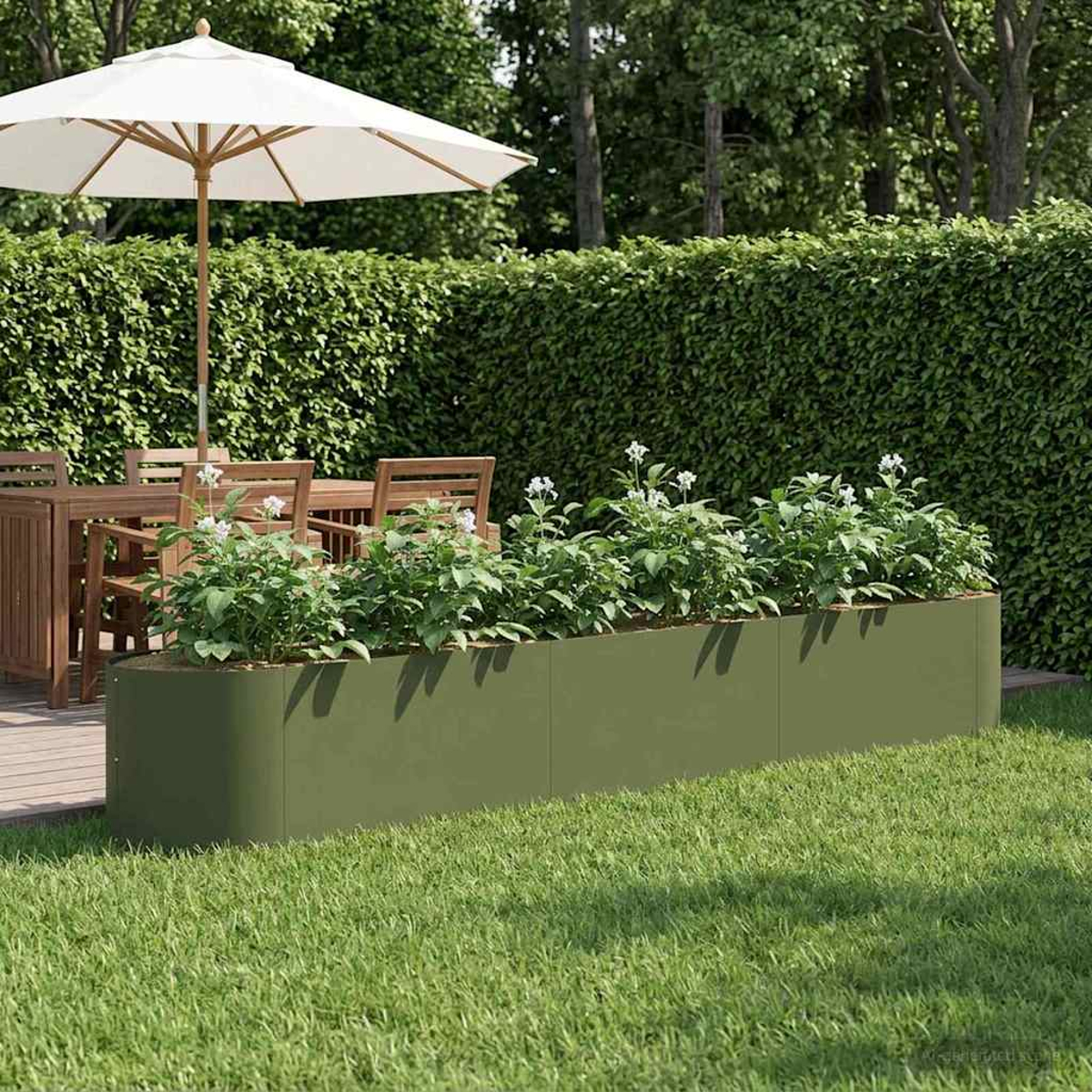 Grüner Pflanzer mit Pflanzen in einem Garten mit Sonnenschirm und Tisch.