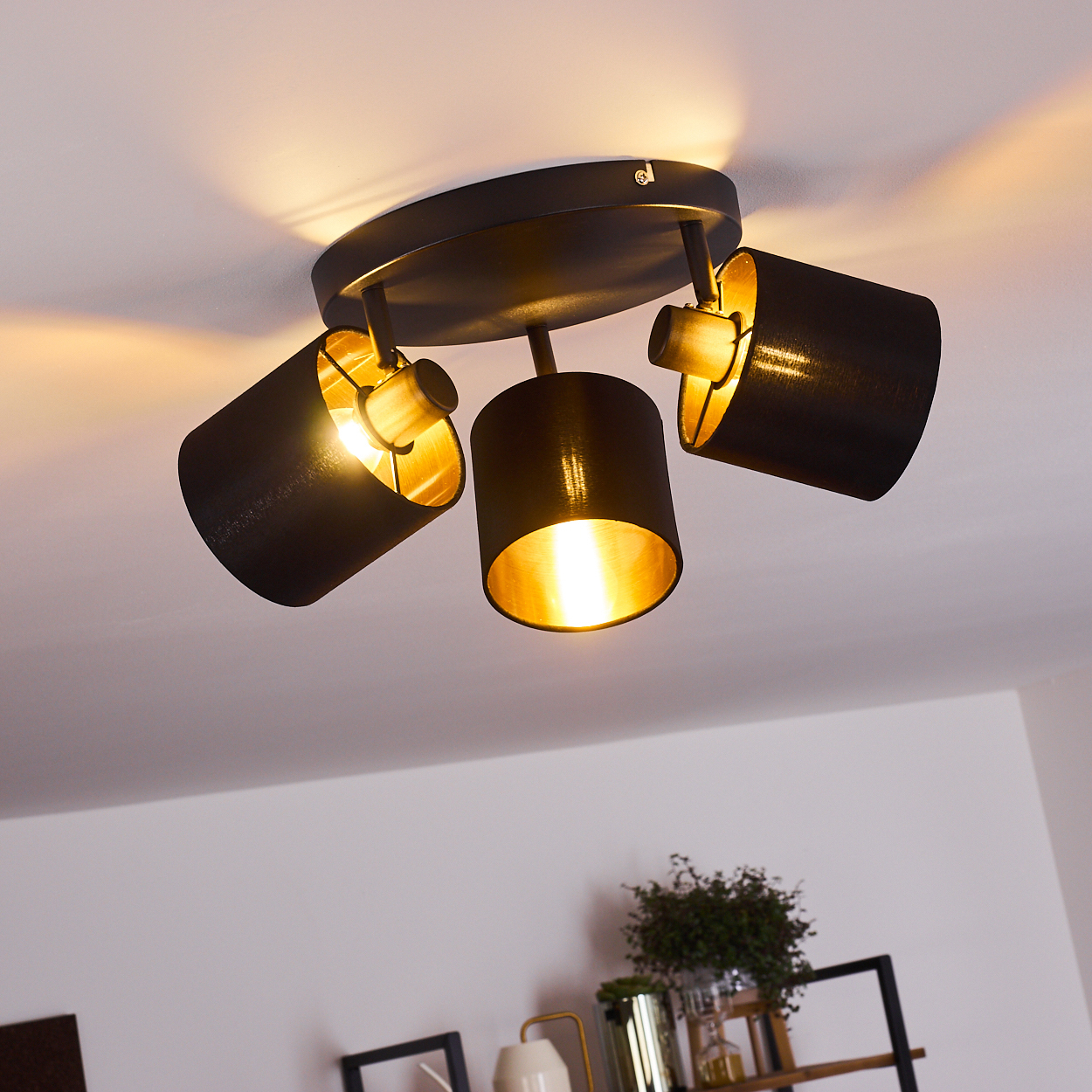 Schwarz orientierbare Deckenleuchte mit drei Lampenschirmen und goldenen Innenseiten.