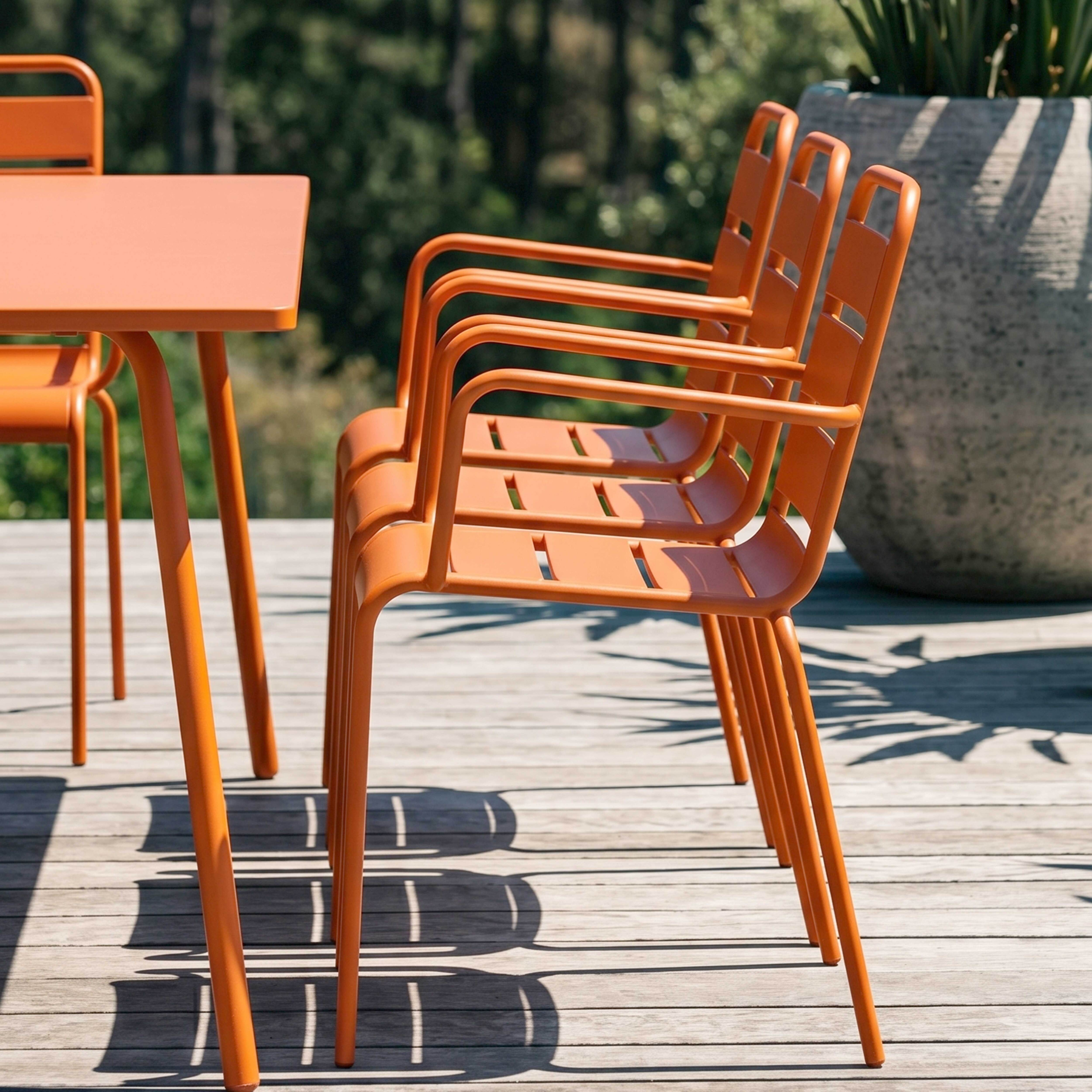 Orange Stühle und Tisch auf Holzdeck mit Schatten von Pflanzen.