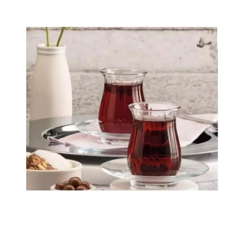 Kırmızı içecekli iki bardak, vazo ve tatlıların yanında tabaklarda duruyor.