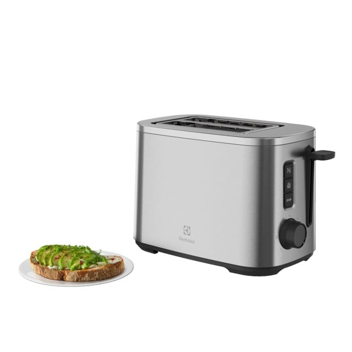 Ein silberner Toaster steht neben einem Teller mit Toast und Avocado.