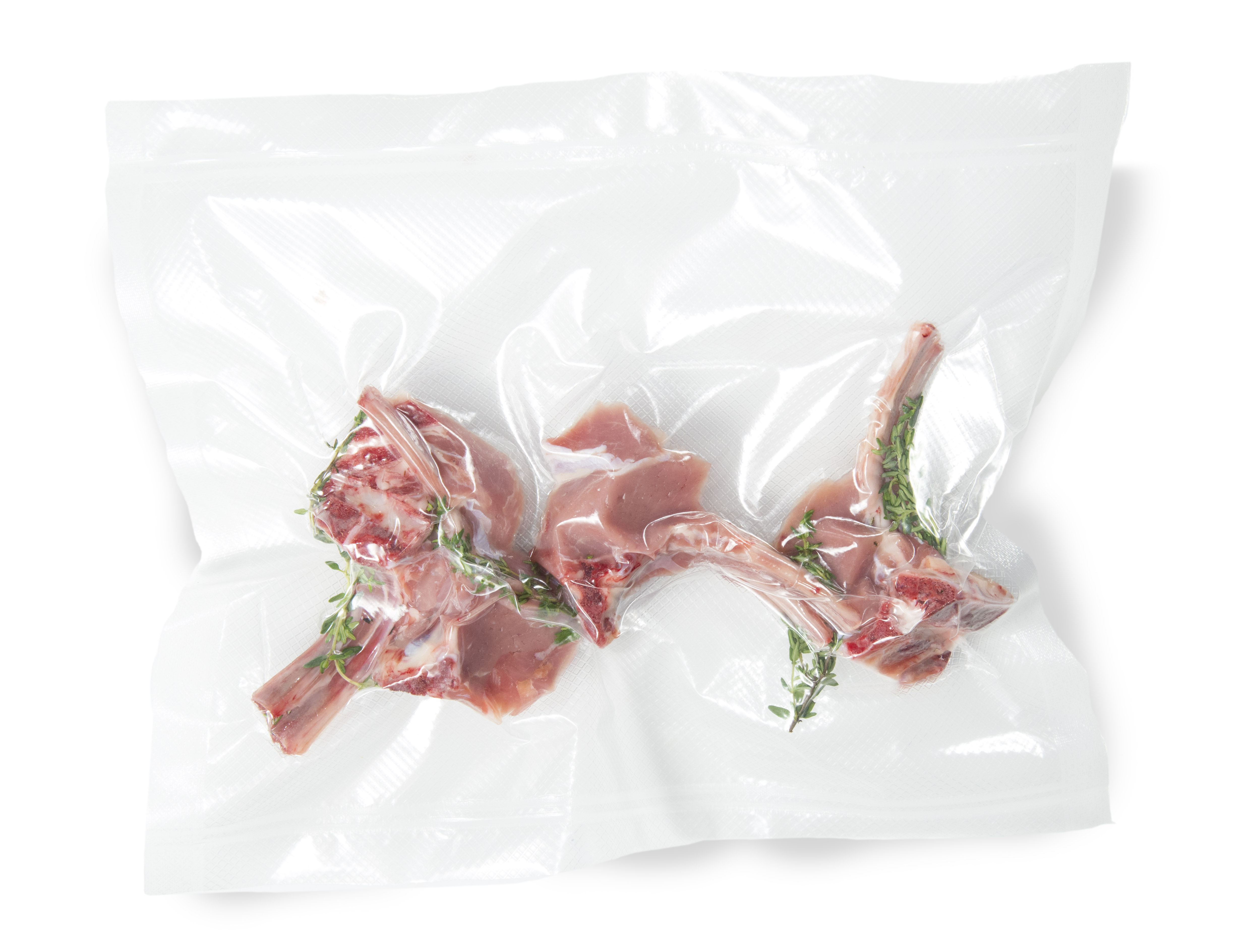Chuletas de cordero crudas con tomillo en una bolsa sellada al vacío.