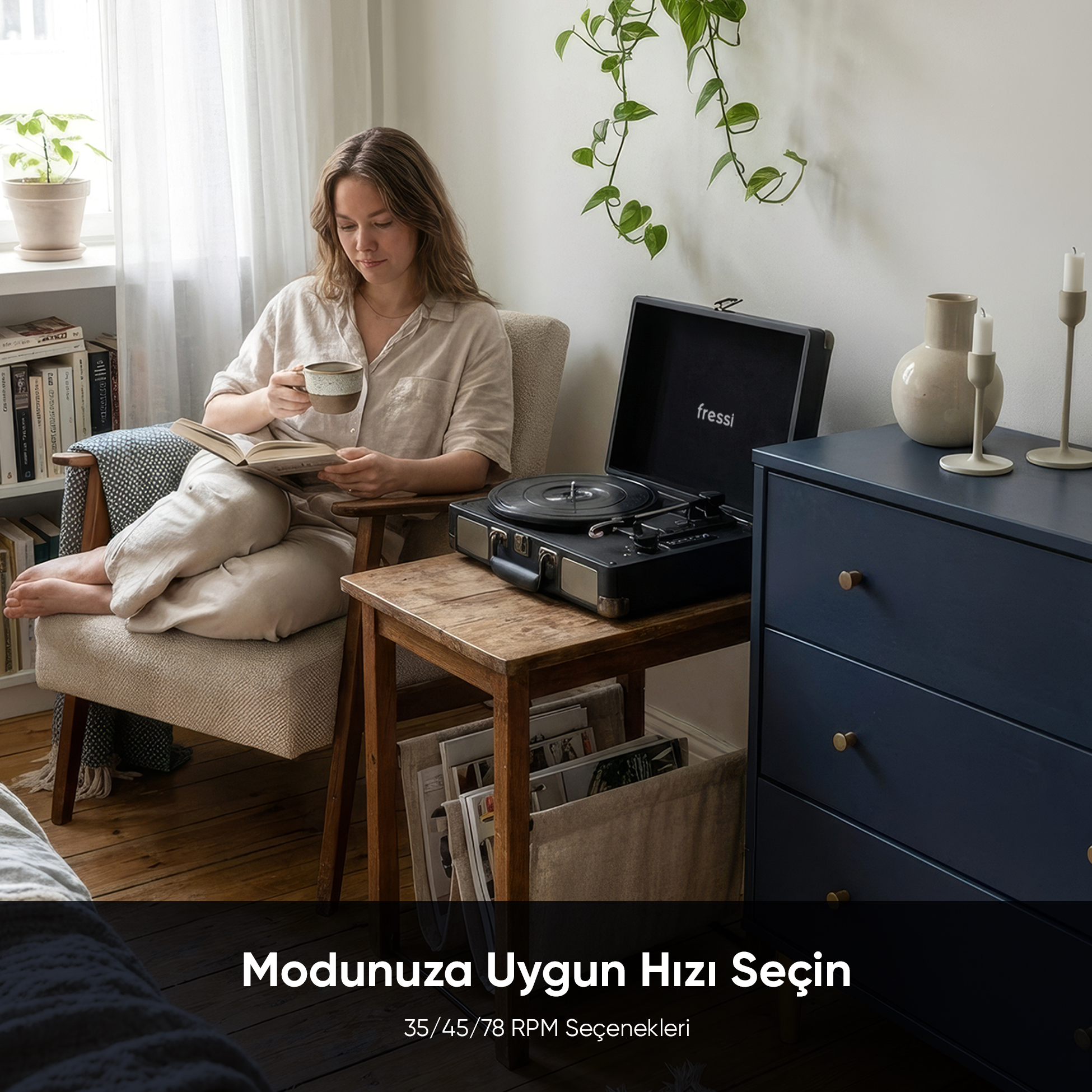 Bir kadın koltukta oturmuş kitap okuyor, pikap yanında kahve içiyor.