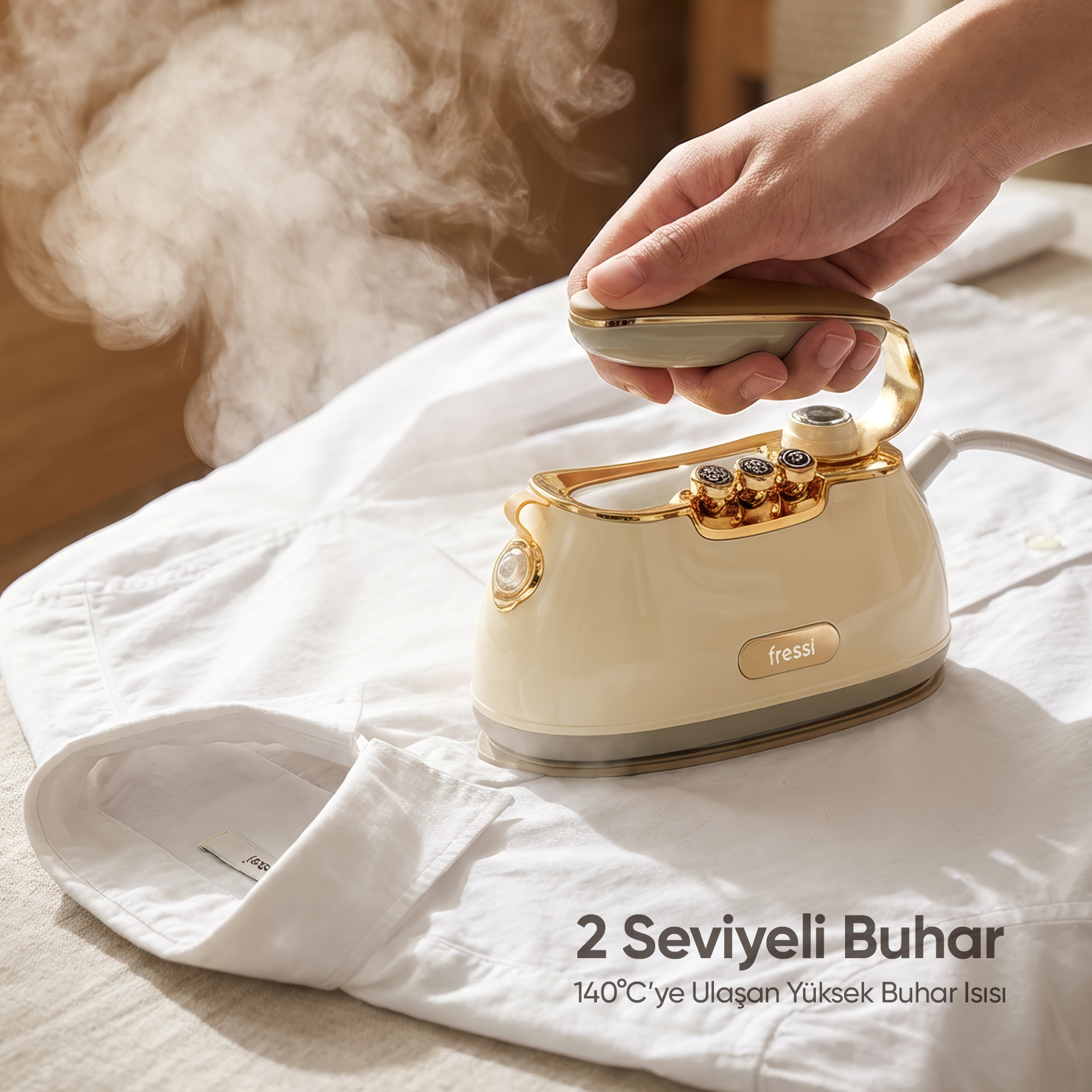 Bir el, buhar çıkaran beyaz bir gömleğin üzerinde krem ve altın rengi ütü tutuyor.