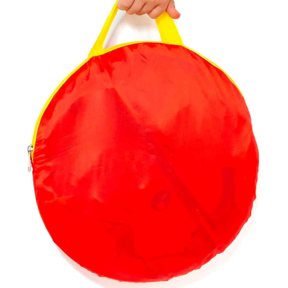 Una bolsa redonda y roja con asas amarillas la sostiene una mano.