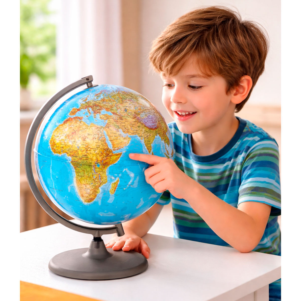 Un niño con una camiseta a rayas azules y verdes señala un globo terráqueo.