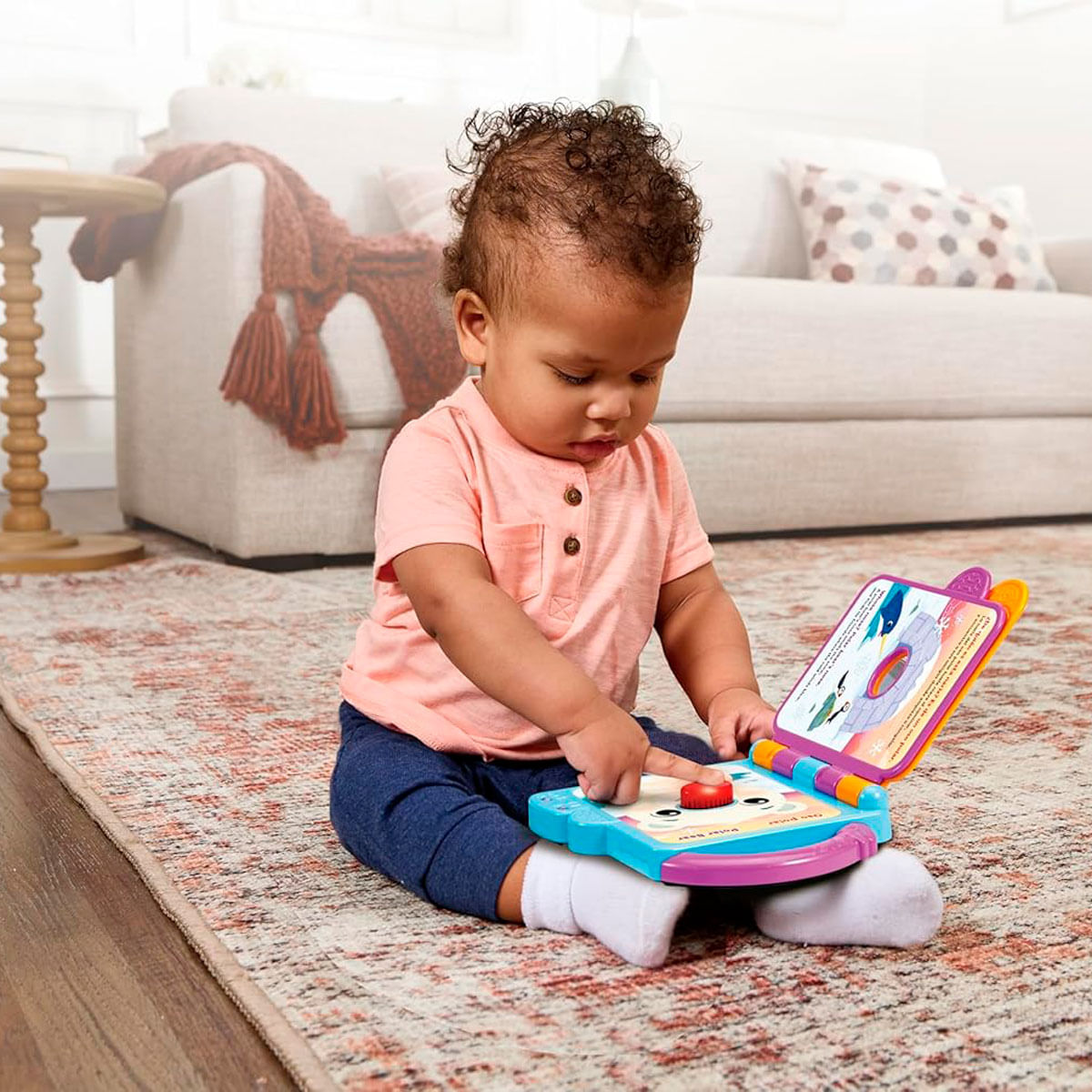 Un bebé se sienta en una alfombra, jugando con un libro interactivo colorido.