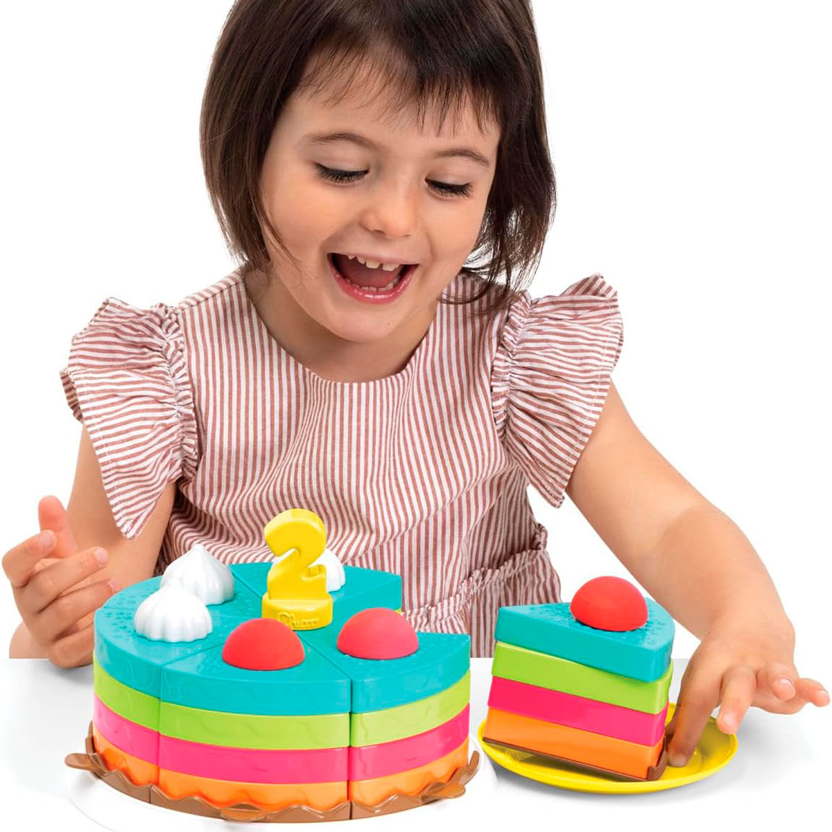 Una niña juega con un pastel de juguete colorido con una vela con el número 2.