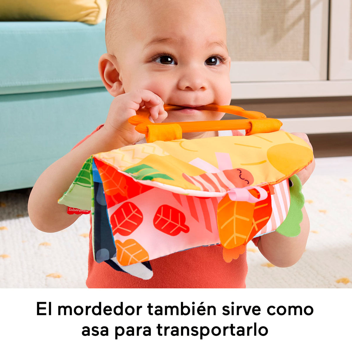 Un bebé muerde un sonajero colorido con asa naranja.