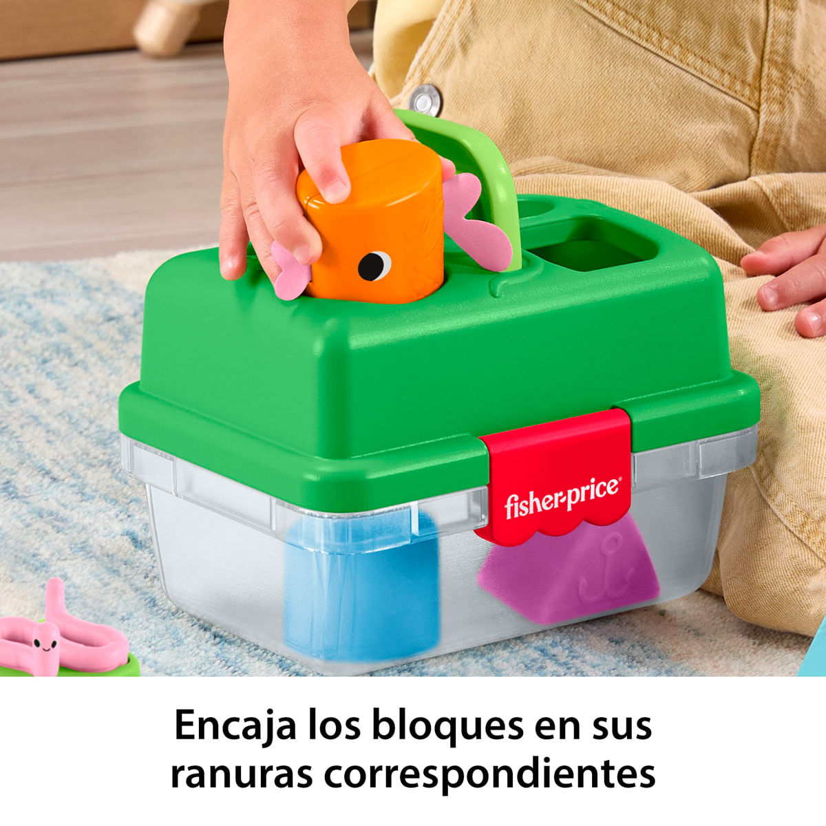 Una mano infantil introduce un bloque naranja de pez en un juguete clasificador de formas.
