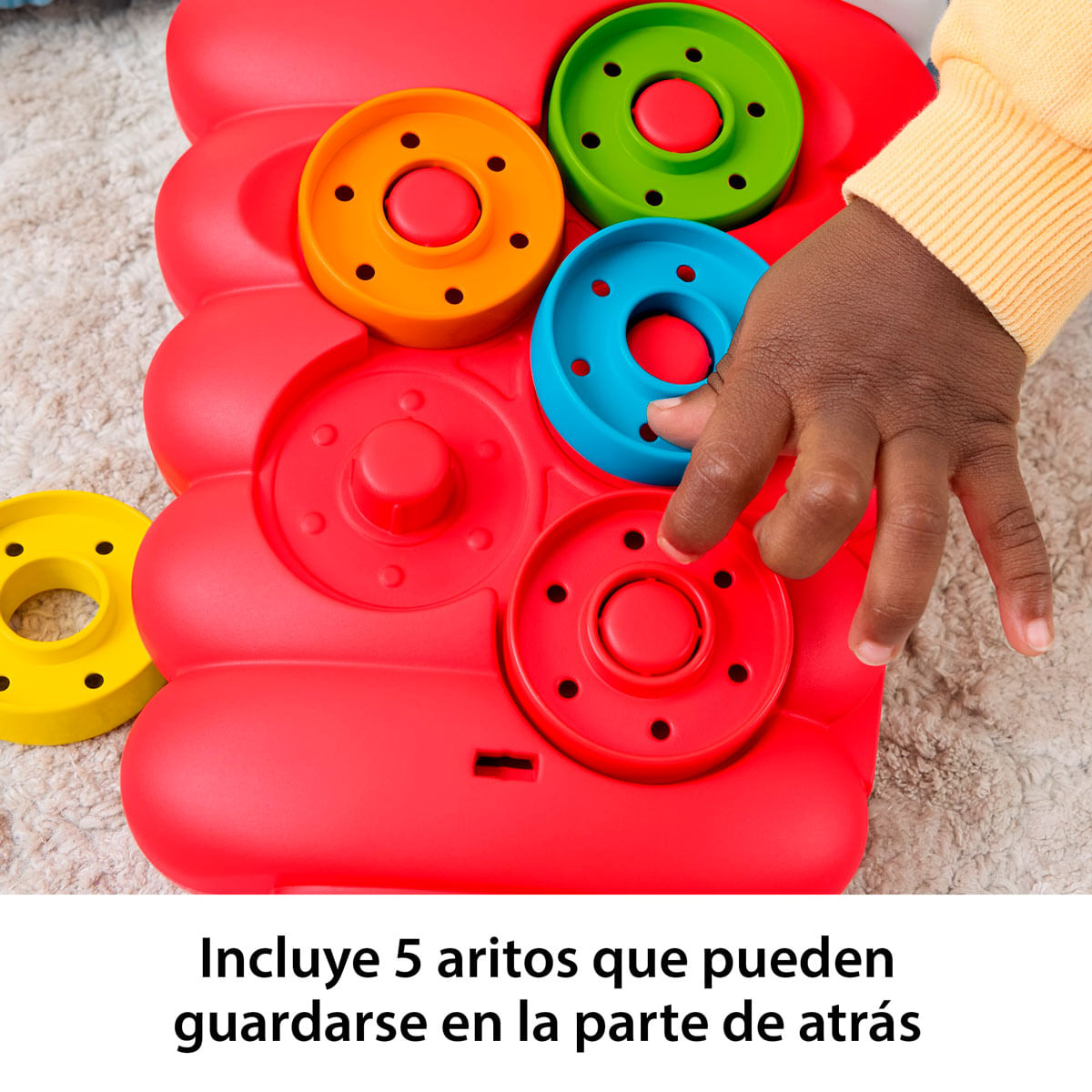Mano de bebé jugando con aros coloridos en juguete rojo.