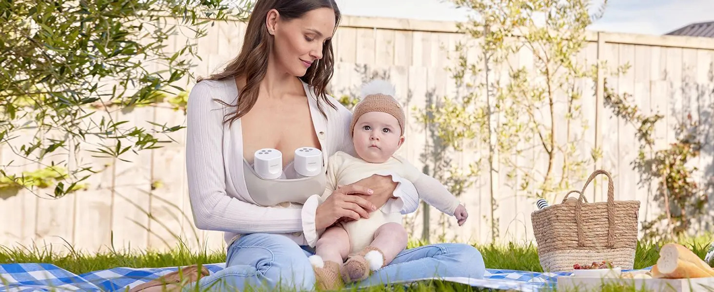 Una donna con un bambino su una coperta all'aperto, che usa un tiralatte.