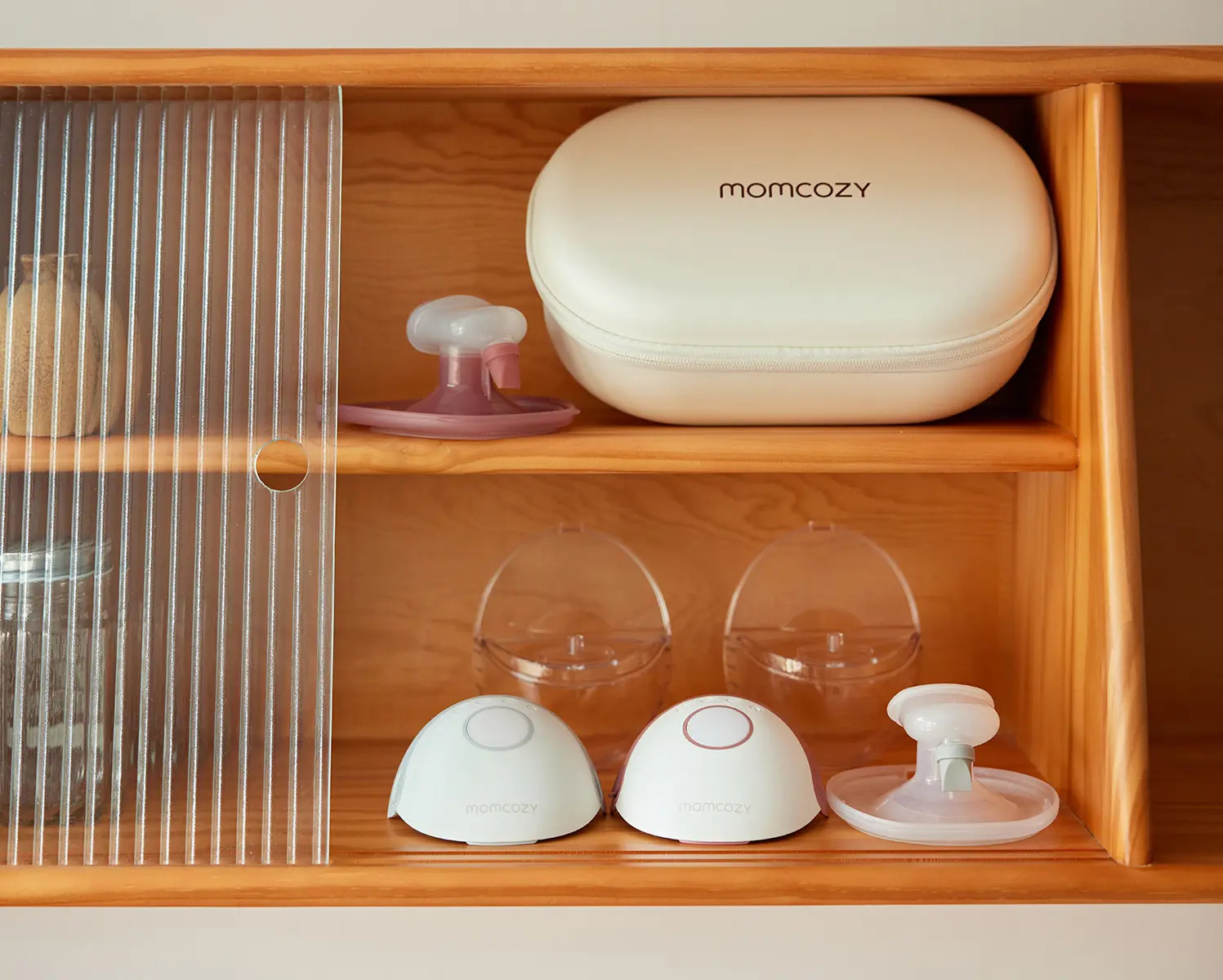Una mensola di legno con prodotti Momcozy: una custodia, due pompe e un accessorio.