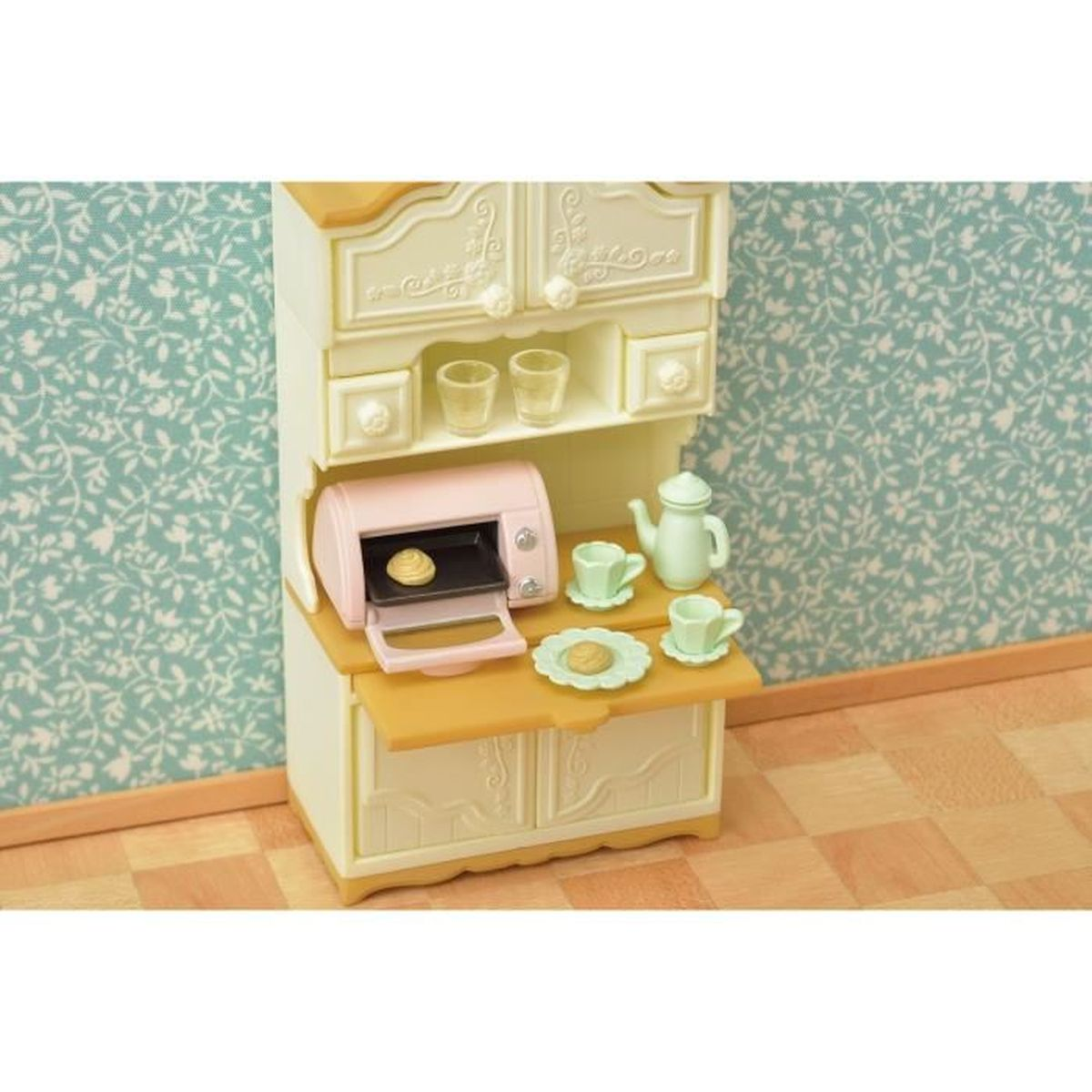 Escena de cocina en miniatura con horno rosa, tetera, tazas y galletas.