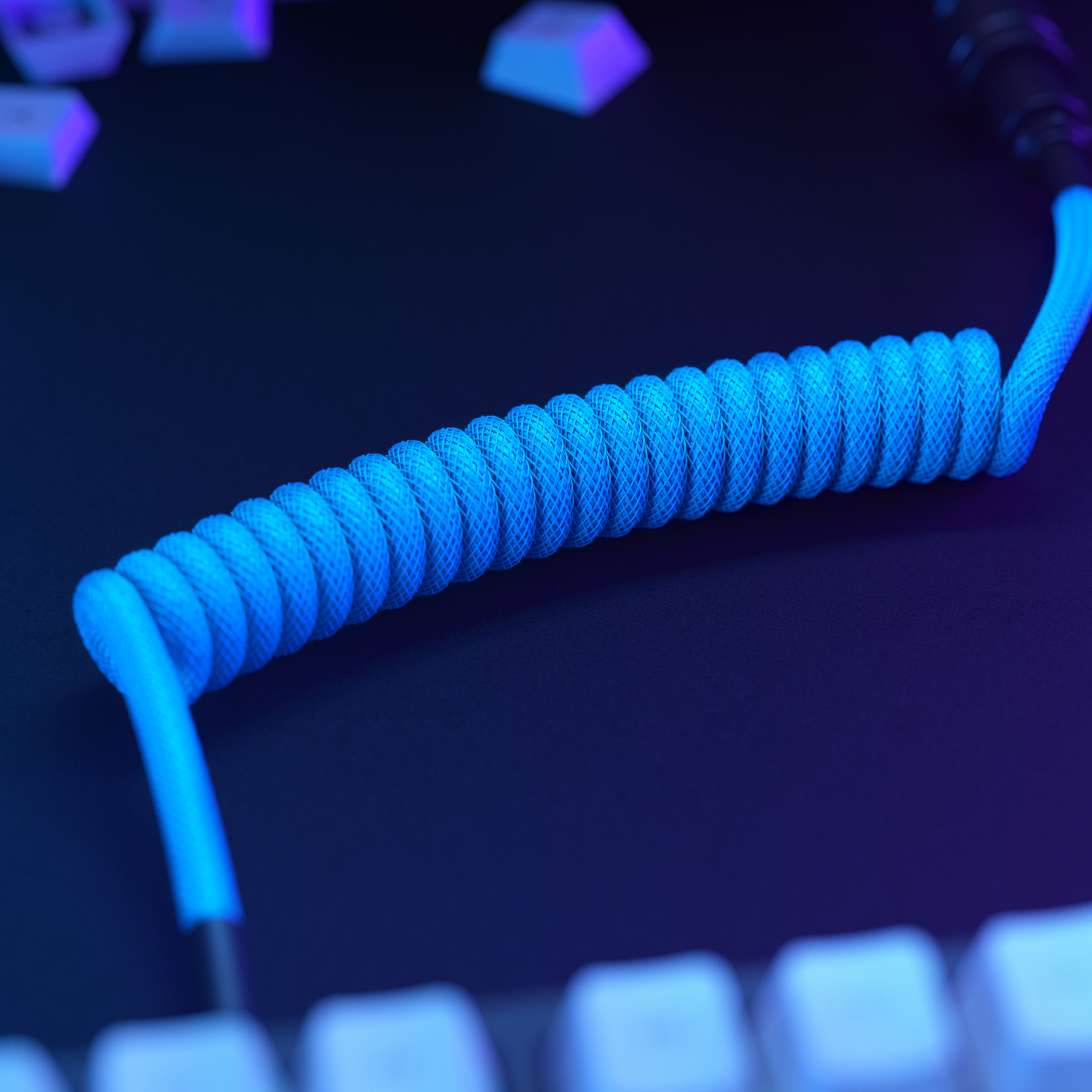 Kıvrımlı, parlak mavi USB kablosu, klavye tuşlarının olduğu karanlık yüzeyde.