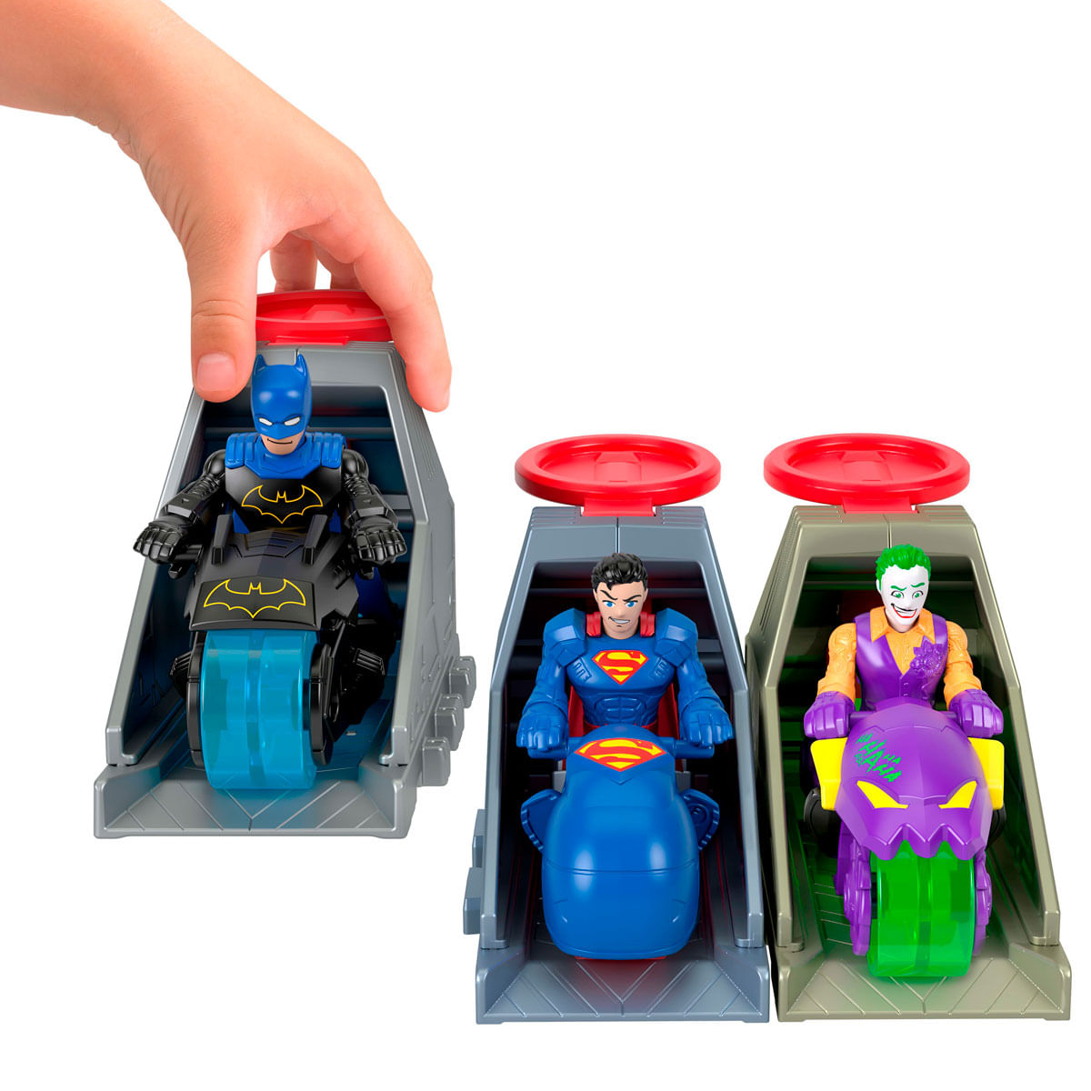 La mano de un niño opera un lanzador para figuras de acción de Batman, Superman y Joker en motocicletas.