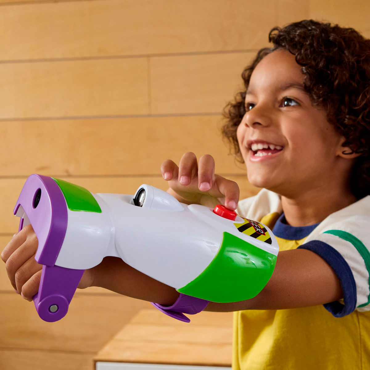 Un niño de pelo rizado juega con una pistola de juguete Buzz Lightyear en el brazo.