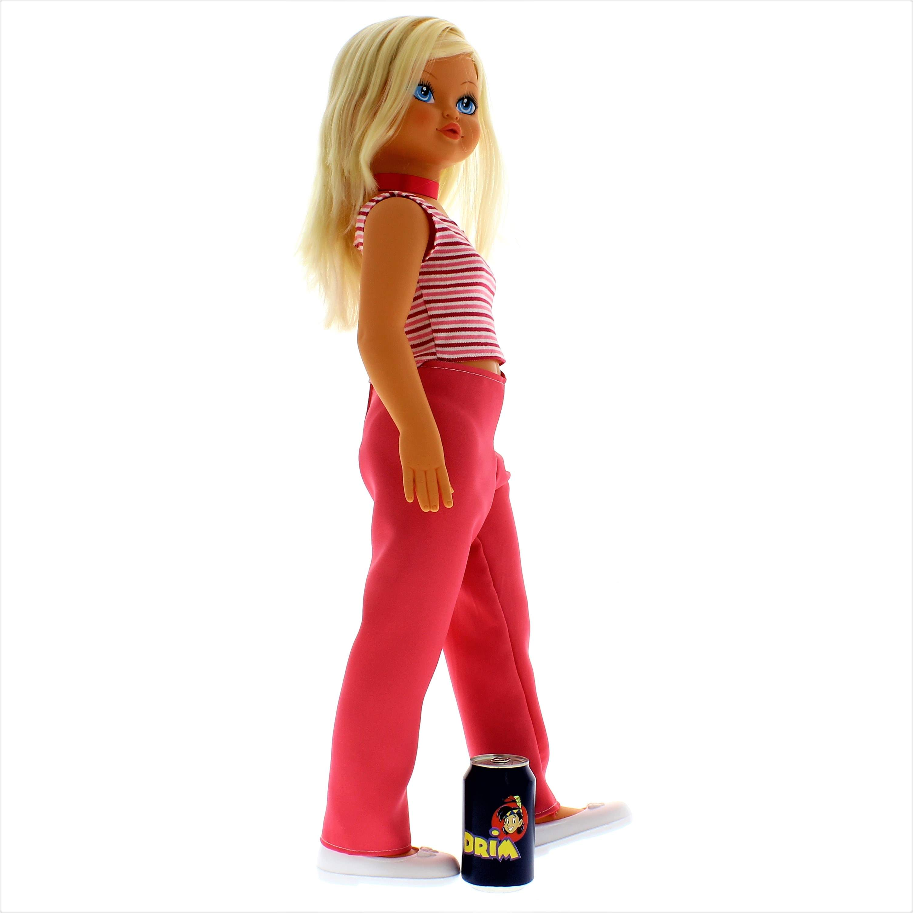 Una muñeca rubia con top azul y pantalón rosa está al lado de una lata.