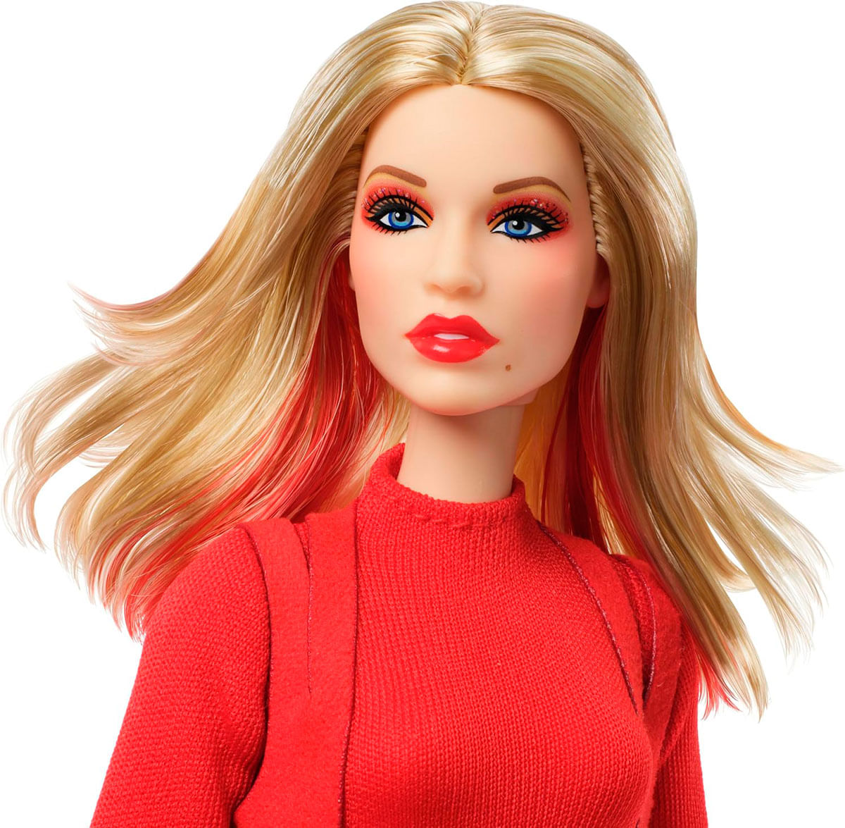 Una muñeca con cabello rubio y mechas rojas, vestida con un suéter rojo.