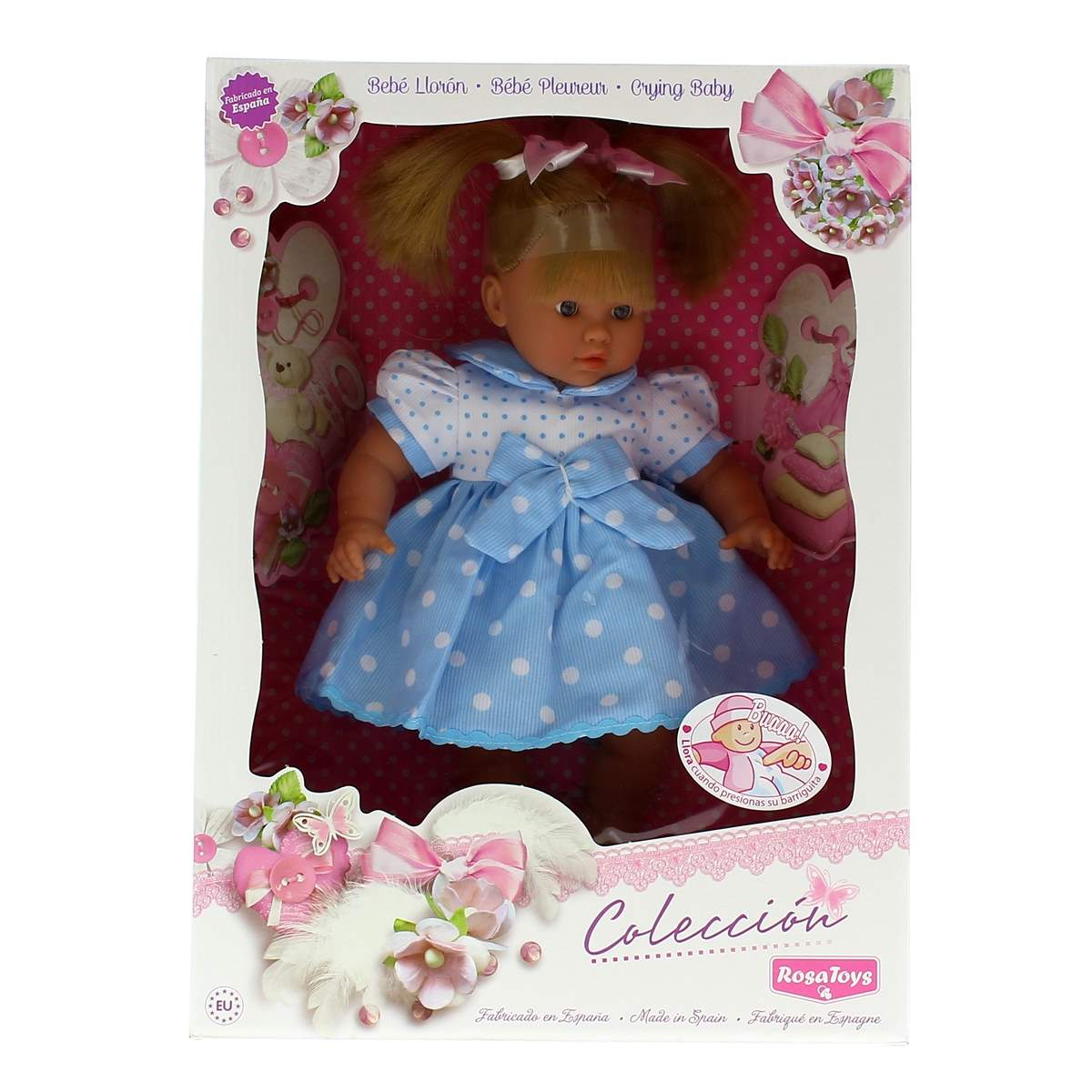 Una muñeca bebé con vestido azul de lunares, en su caja.