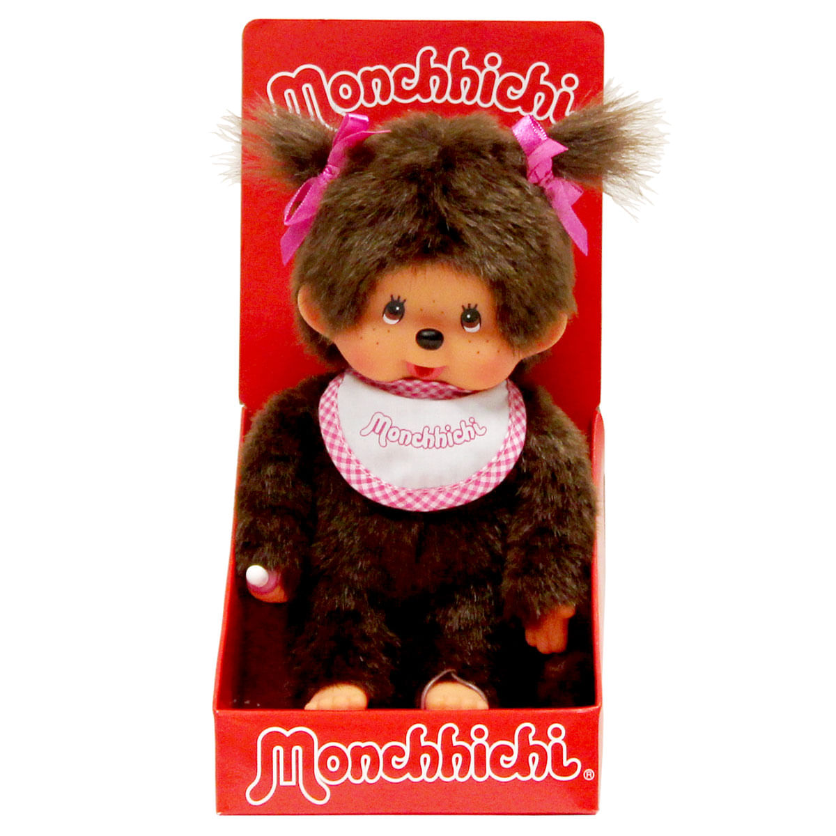 Un bebé Monchhichi peludo marrón con lazos rosas y babero, en embalaje rojo.