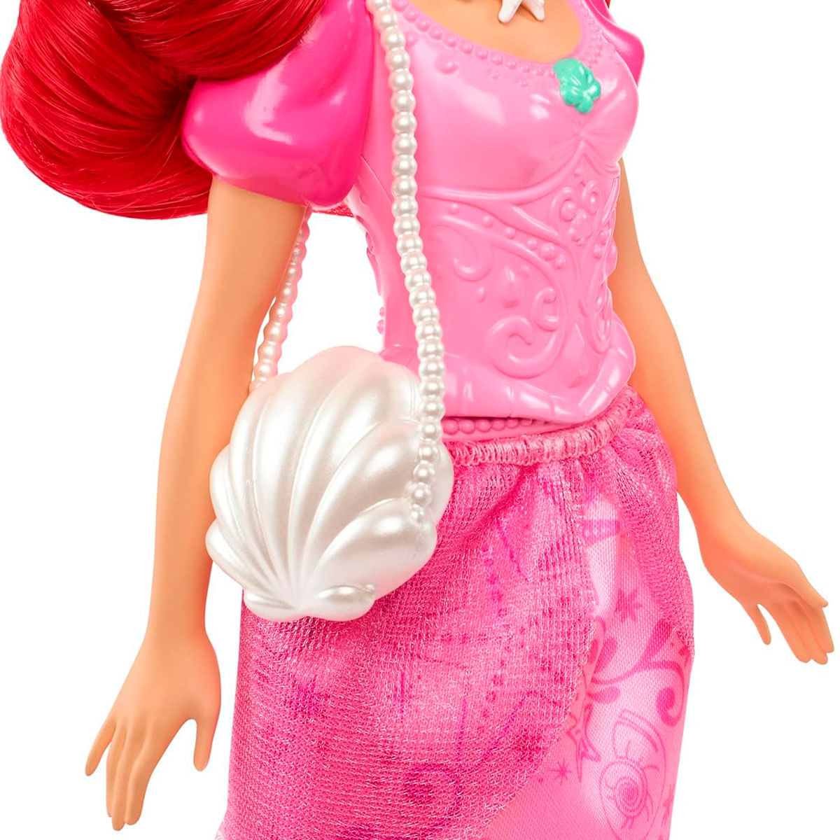 Una muñeca de pelo rojo brillante, con vestido rosa y bolso con forma de concha.