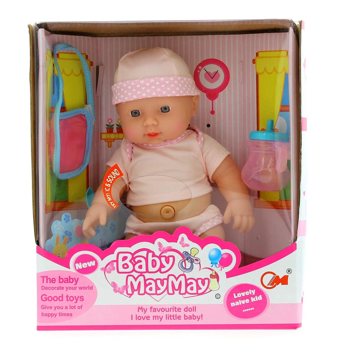 Una muñeca bebé con ropa rosa se sienta en una caja con accesorios como biberón y bolso.