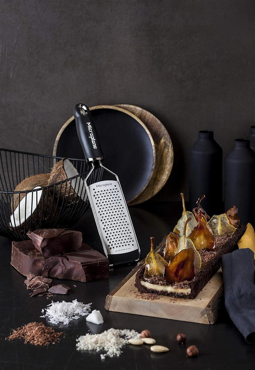 Ein Kasten mit kandierten Birnen, Schokolade, Kokosraspeln und einem Grater.