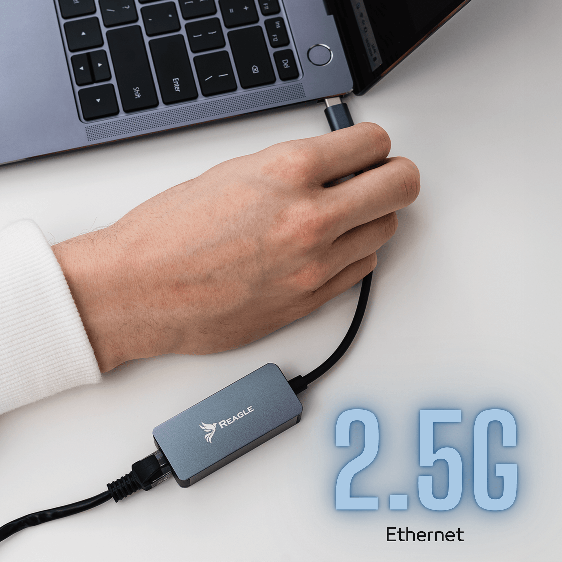 Una mano conecta un cable USB-C gris a un portátil. Un adaptador Ethernet está conectado.