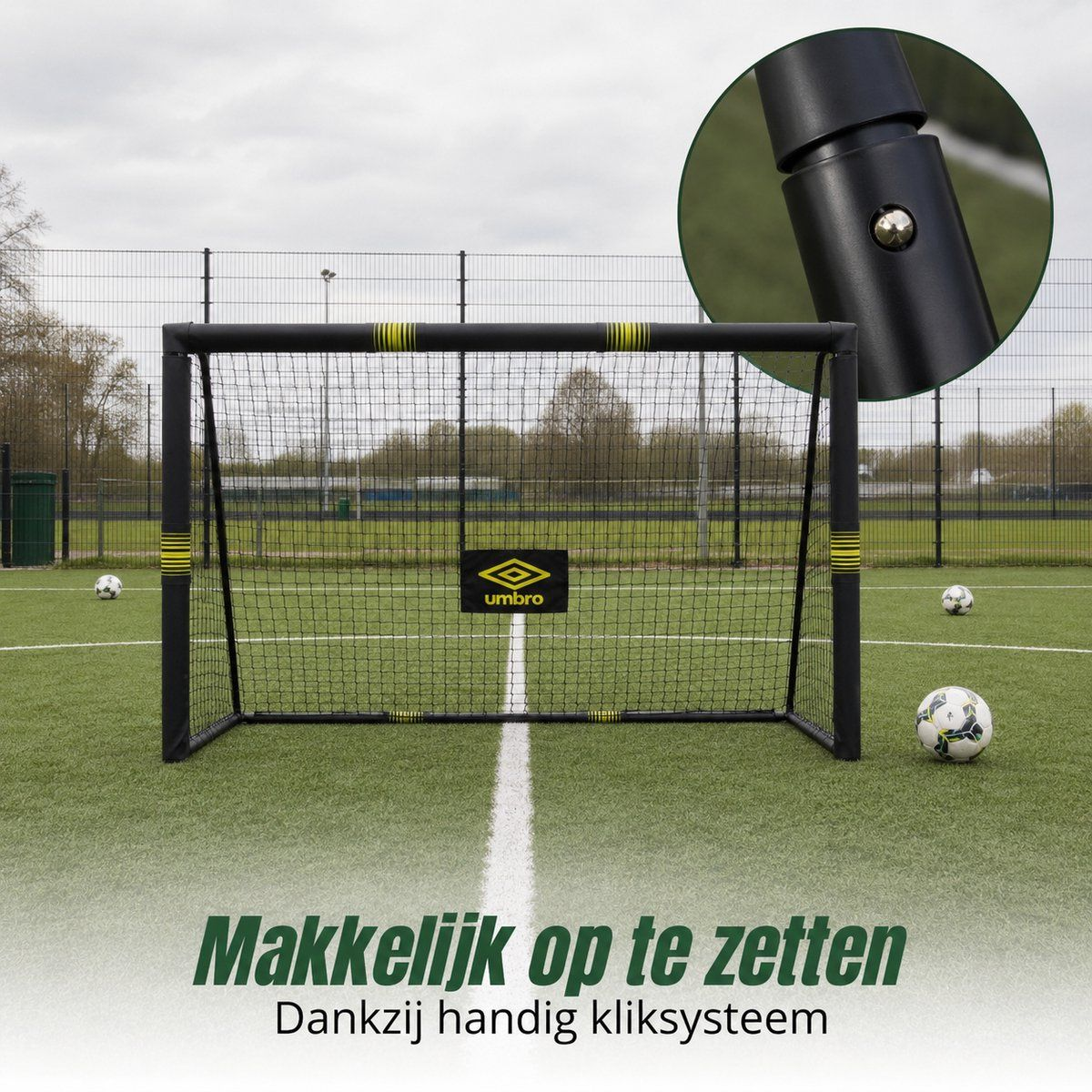 Soccer goal with net and Umbro logo on artificial turf. Several soccer balls and fence in background.