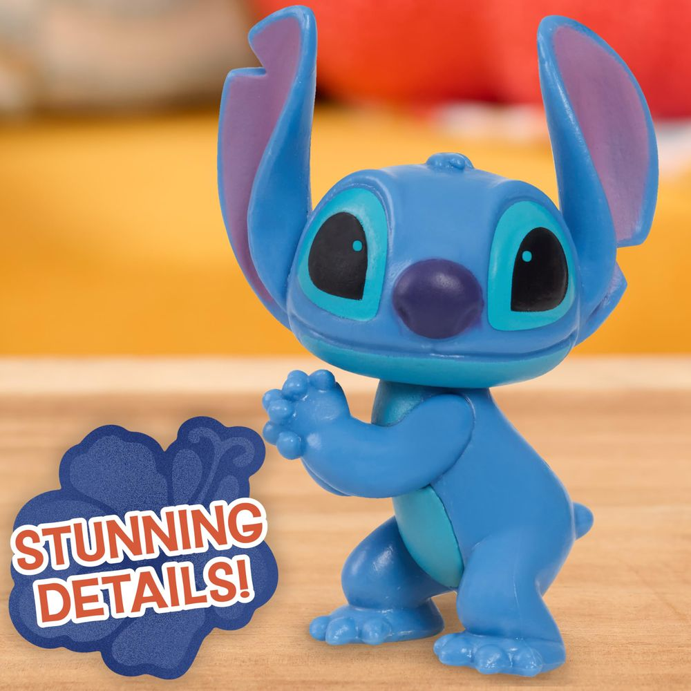Una figura de juguete azul de Stitch con orejas grandes y ojos negros sobre madera.