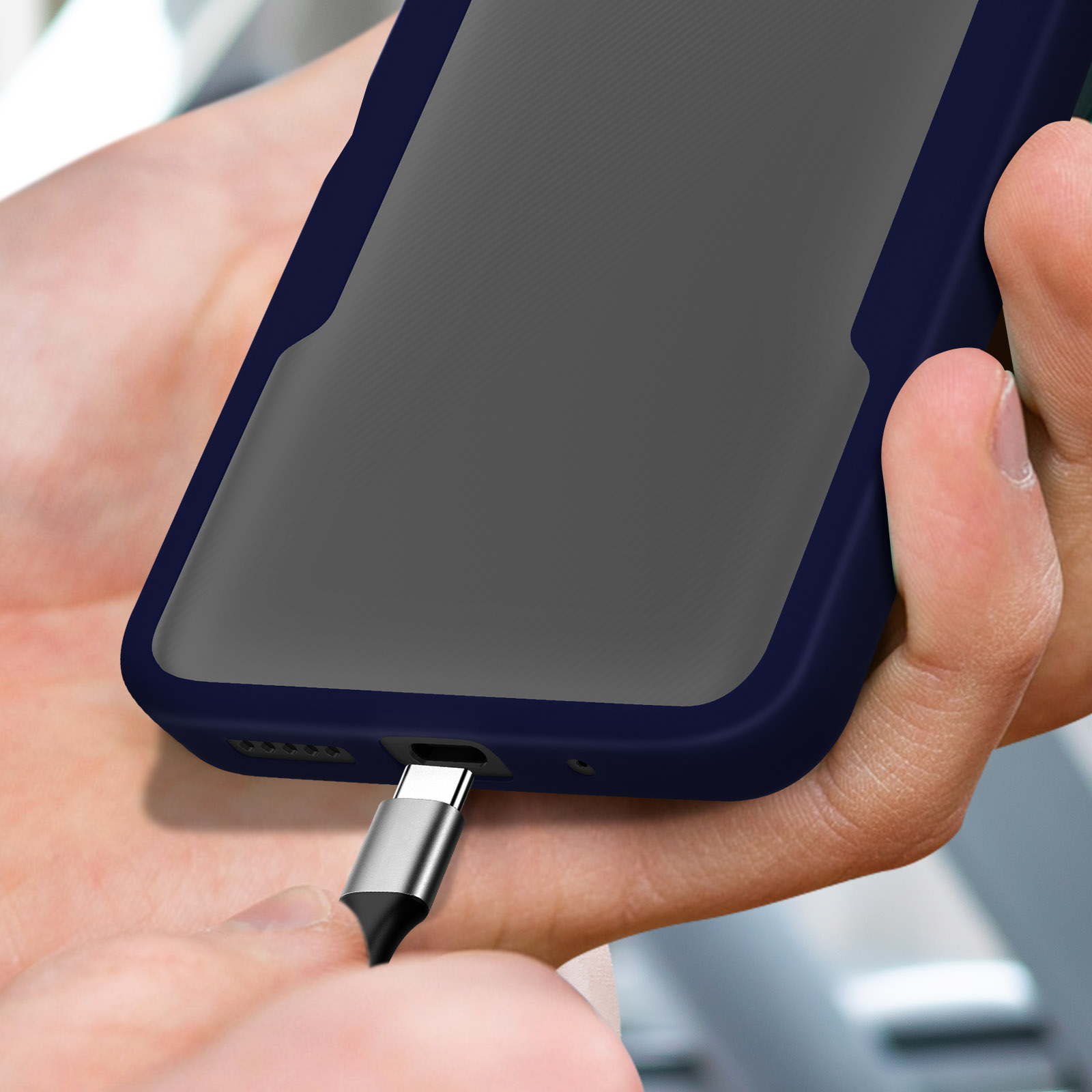 Una mano inserisce un cavo USB-C in un telefono scuro.