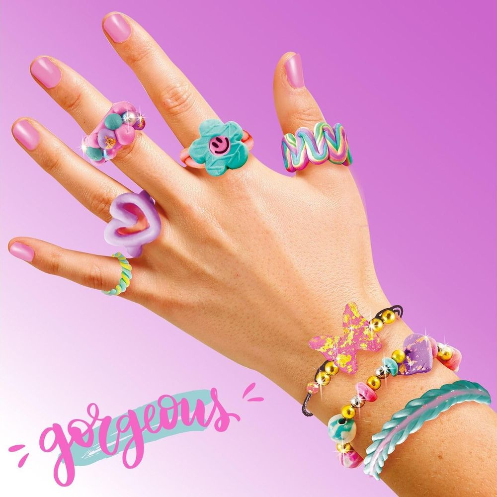 Una mano adornada con anillos y pulseras coloridas sobre fondo morado.