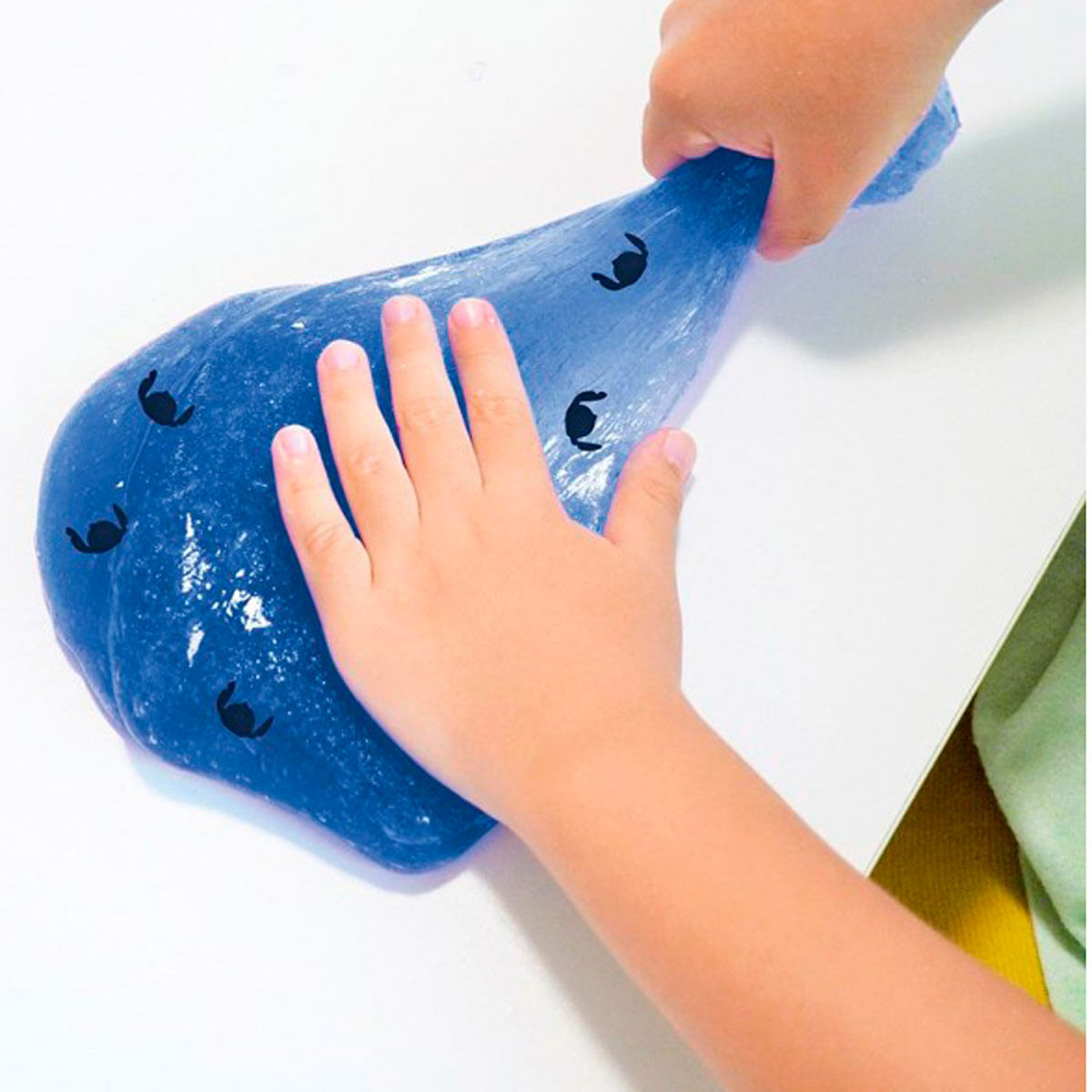 Masa azul con figuras negras es sostenida por manos infantiles.